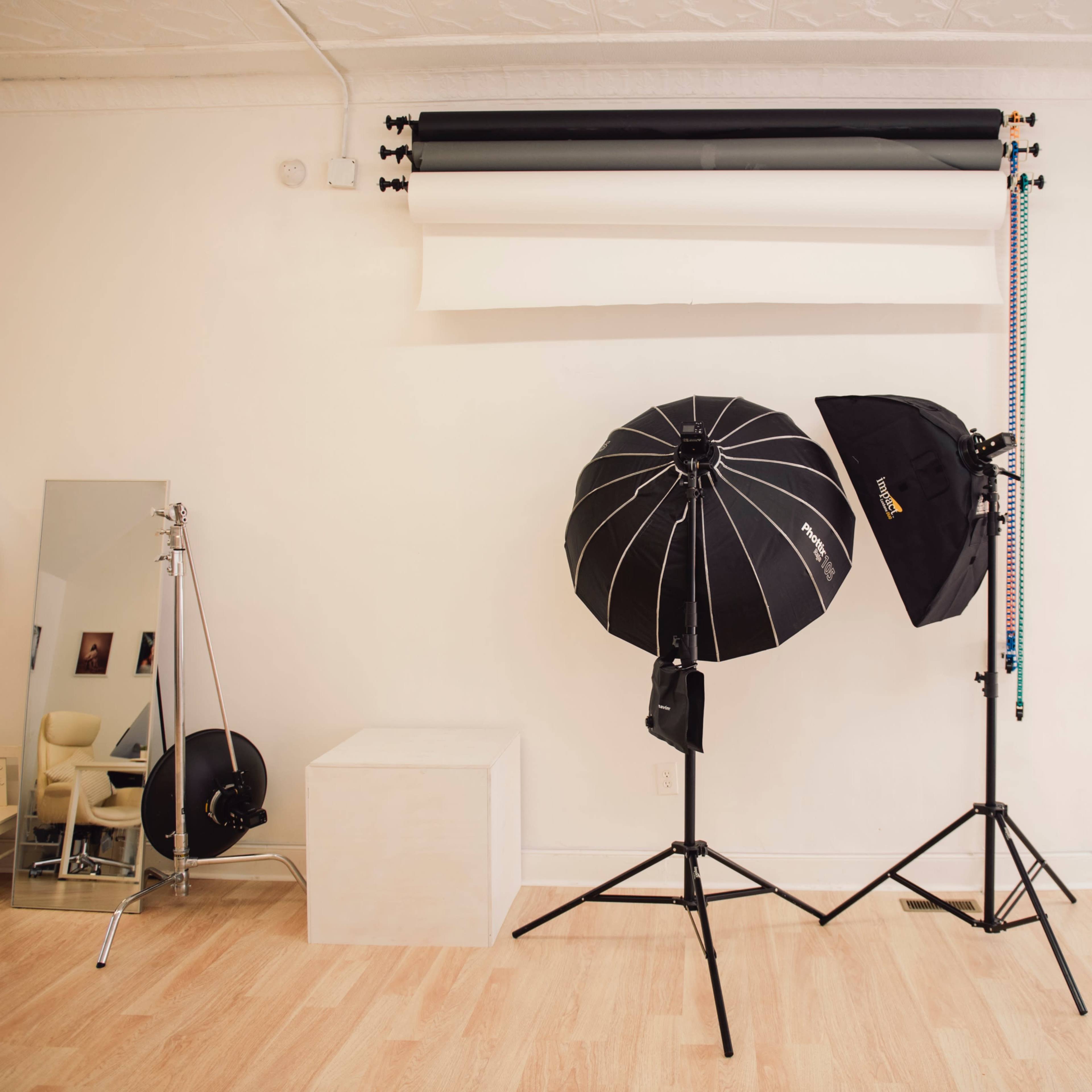 A photography studio setup with two light stands, a white background, and various lighting equipment.