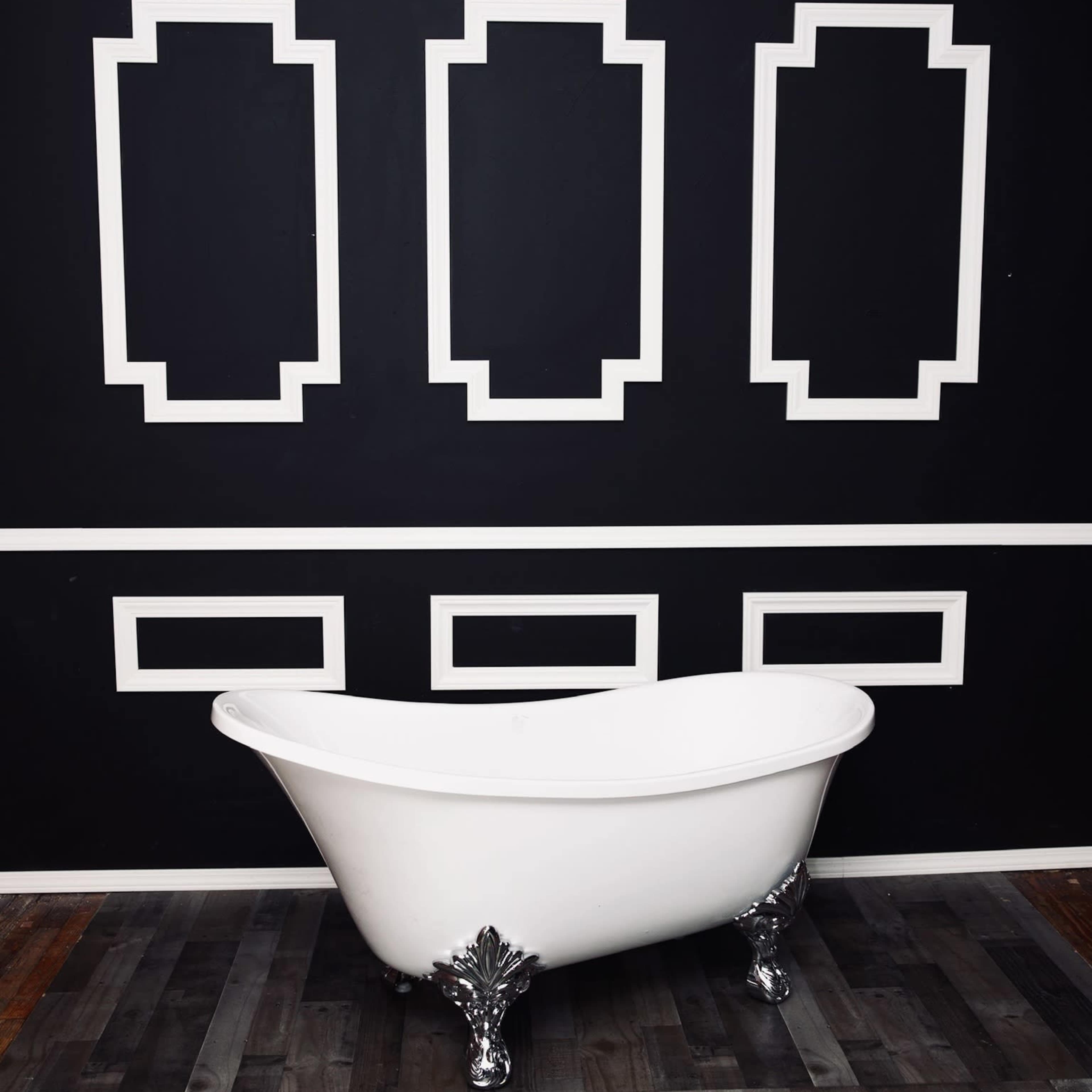 A white freestanding bathtub is positioned on a wooden floor against a black wall featuring white geometric paneling.