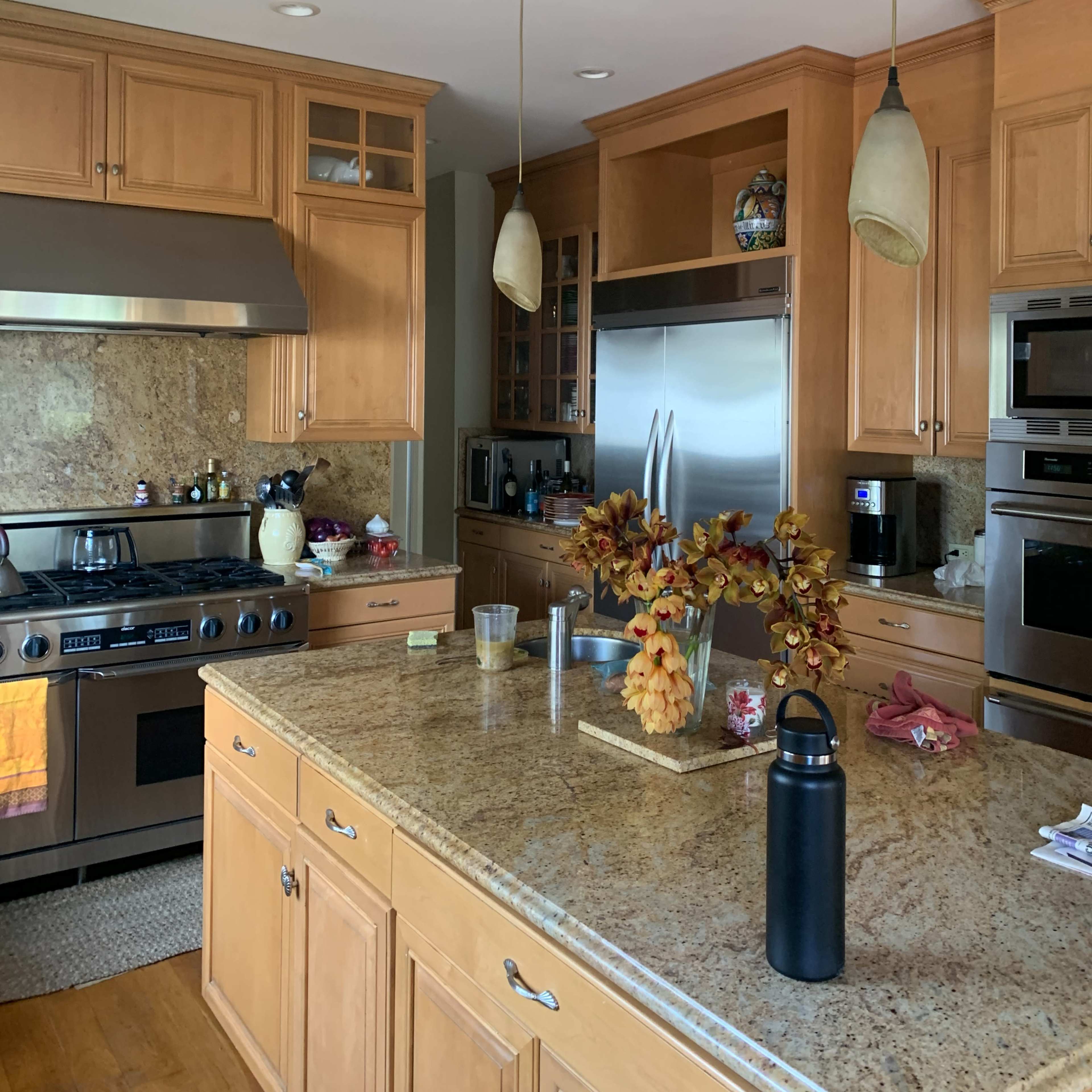A spacious kitchen featuring wooden cabinetry, stainless steel appliances, and a central island adorned with autumn decorations.