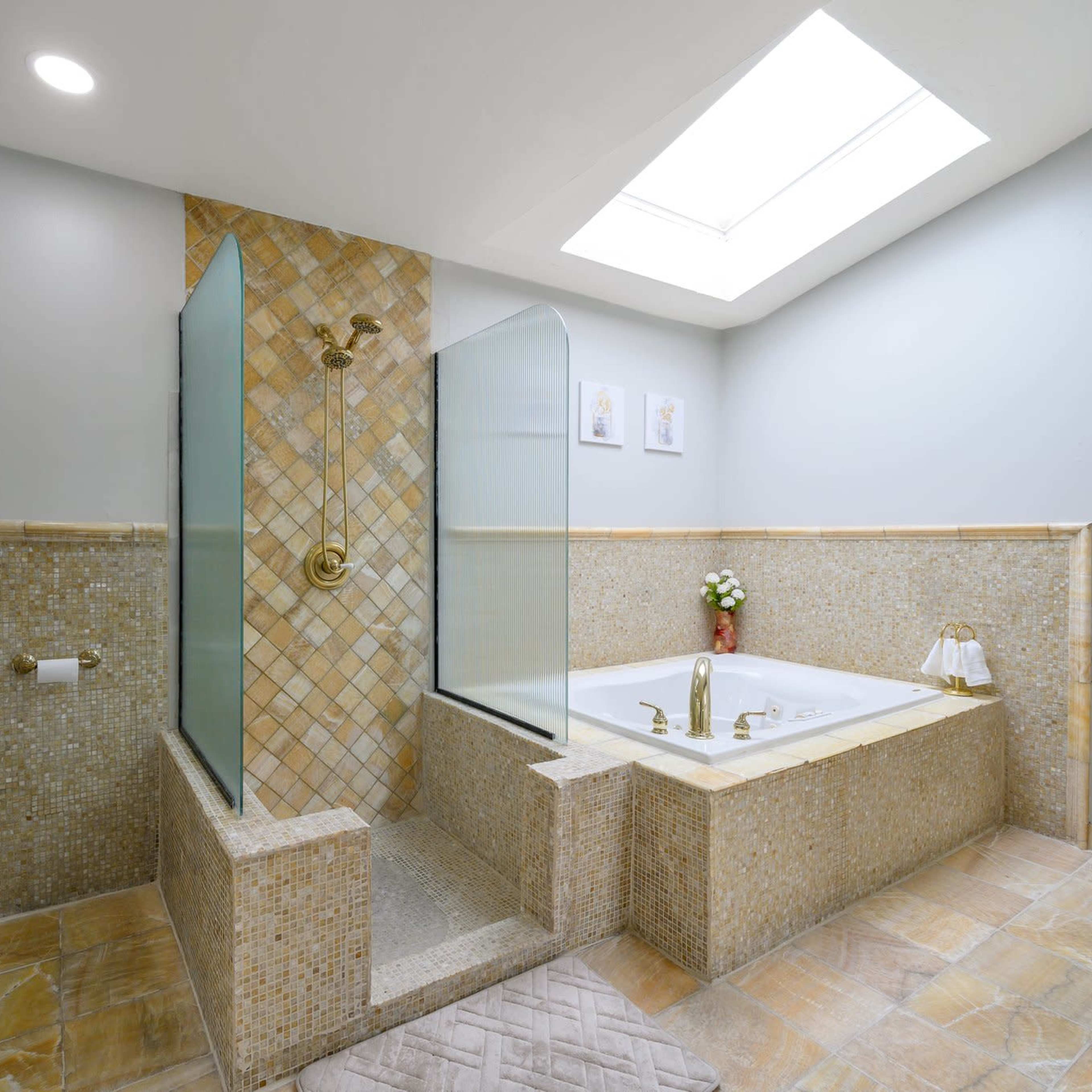 A modern bathroom featuring a glass shower enclosure, a large bathtub, and tiled walls.