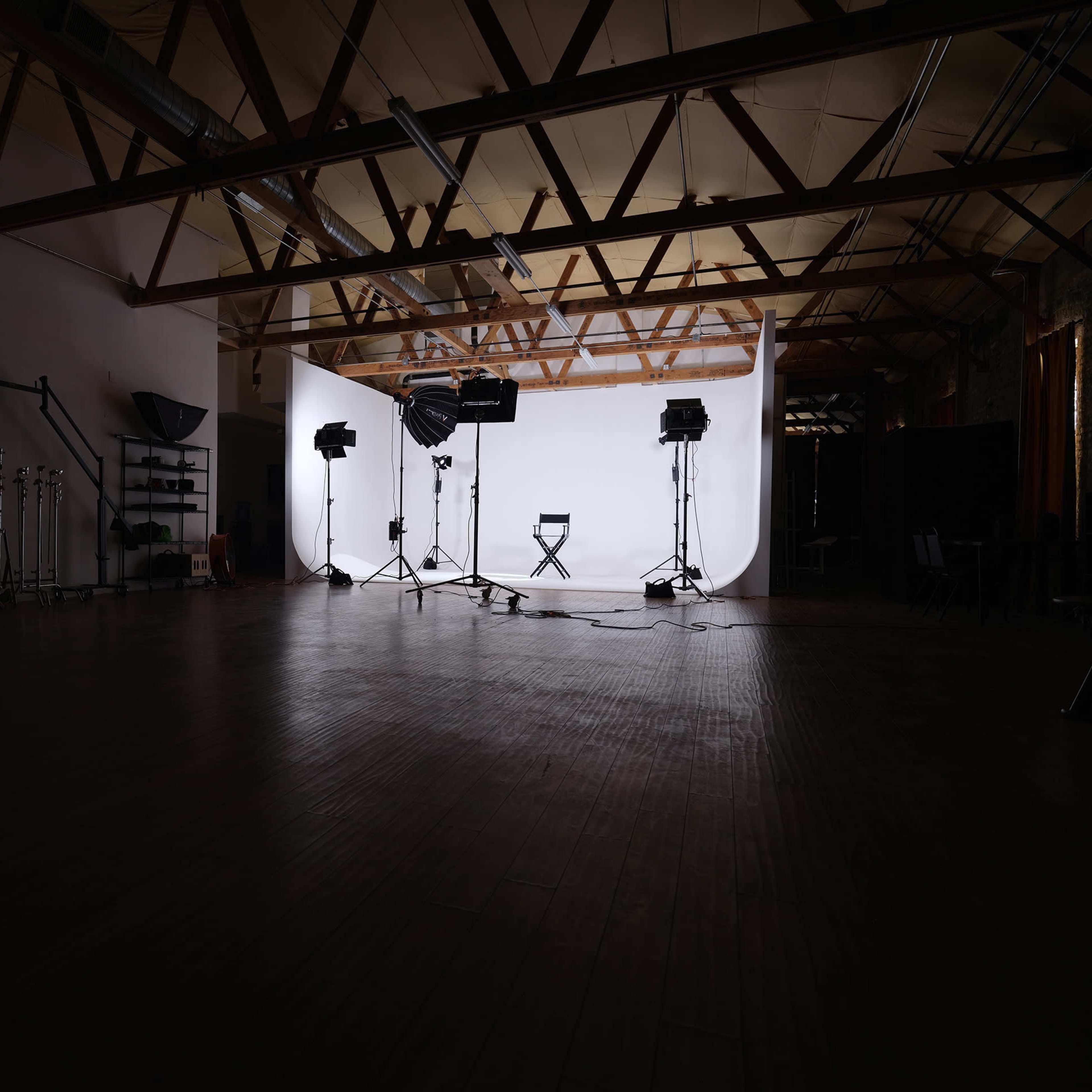 A variety of studio setups with different colored backdrops and lighting arrangements in a spacious interior space.