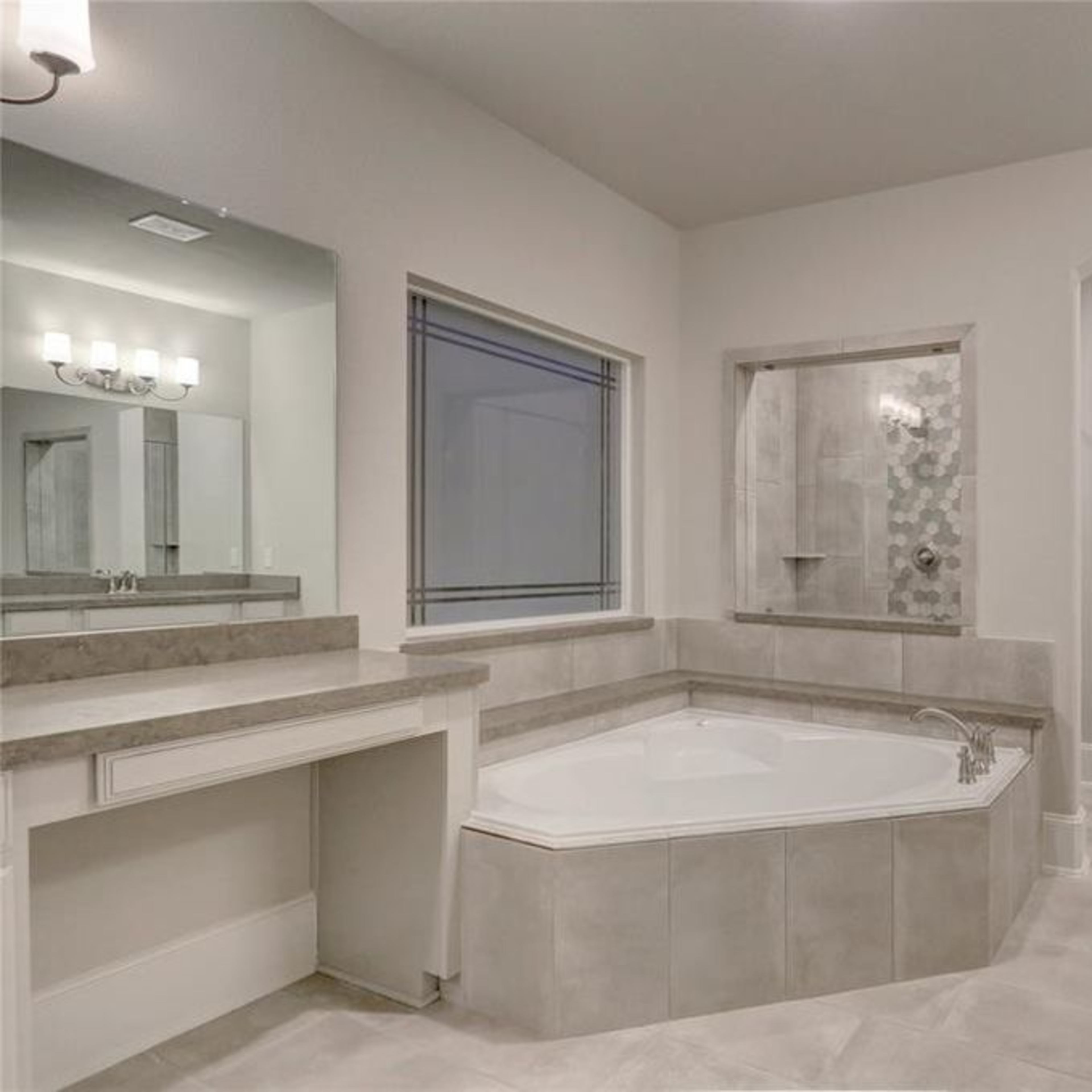 A spacious bathroom featuring a corner bathtub, a separate shower area, and a large mirror with dual sinks.