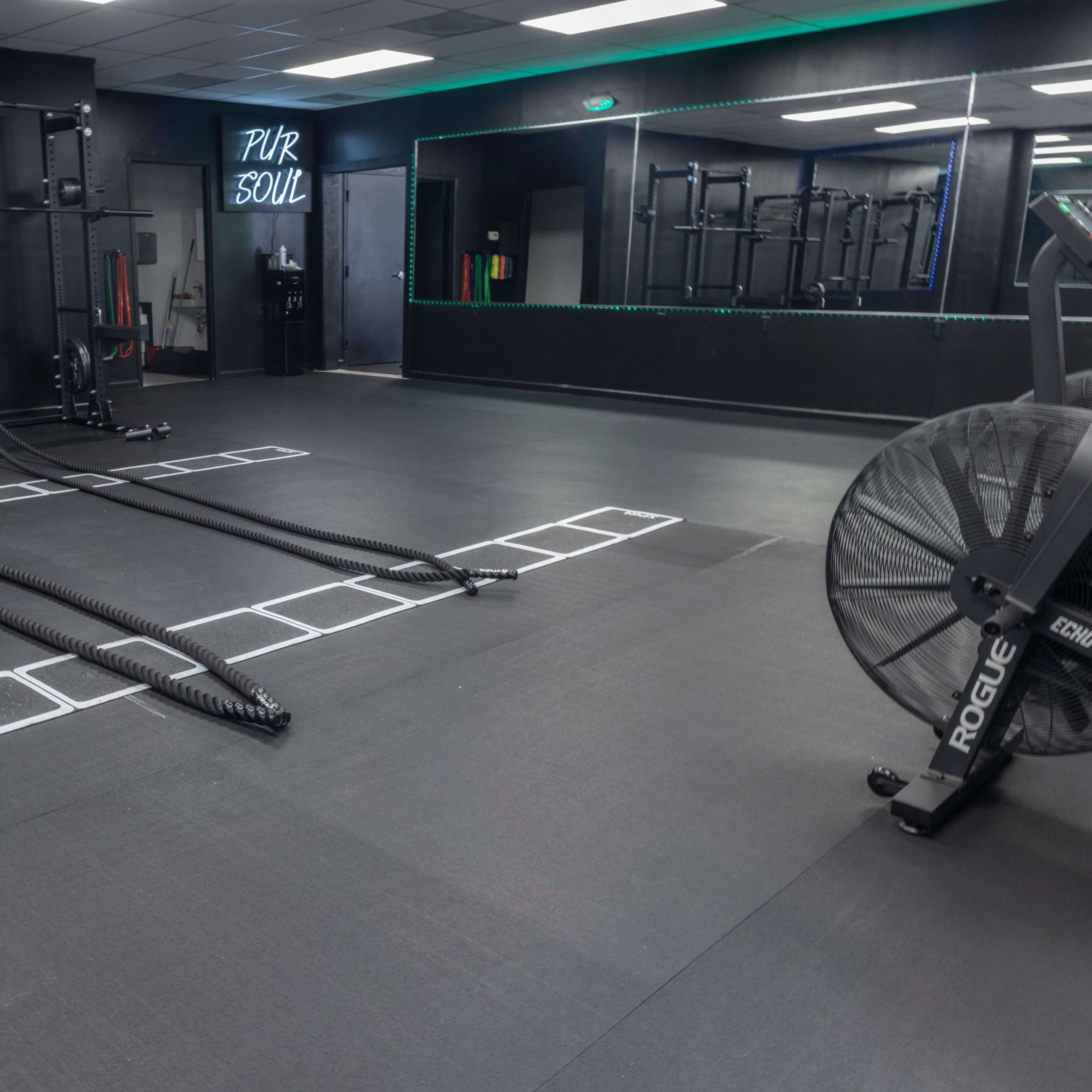 An indoor gym with exercise equipment, including ropes on the floor and a large fan in the corner.