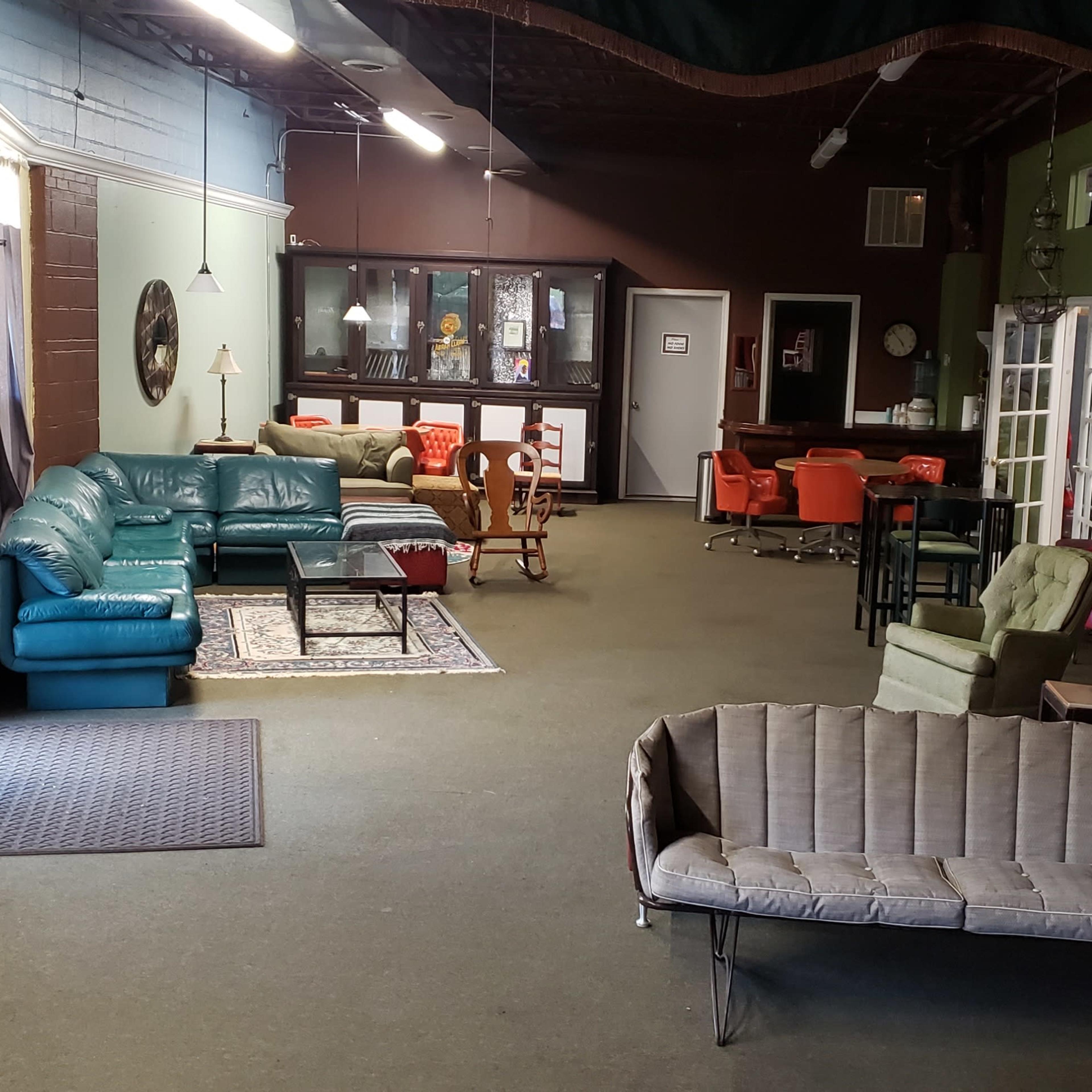 A spacious room divided into two areas featuring various furniture pieces, including sofas, a piano, and a dining table.