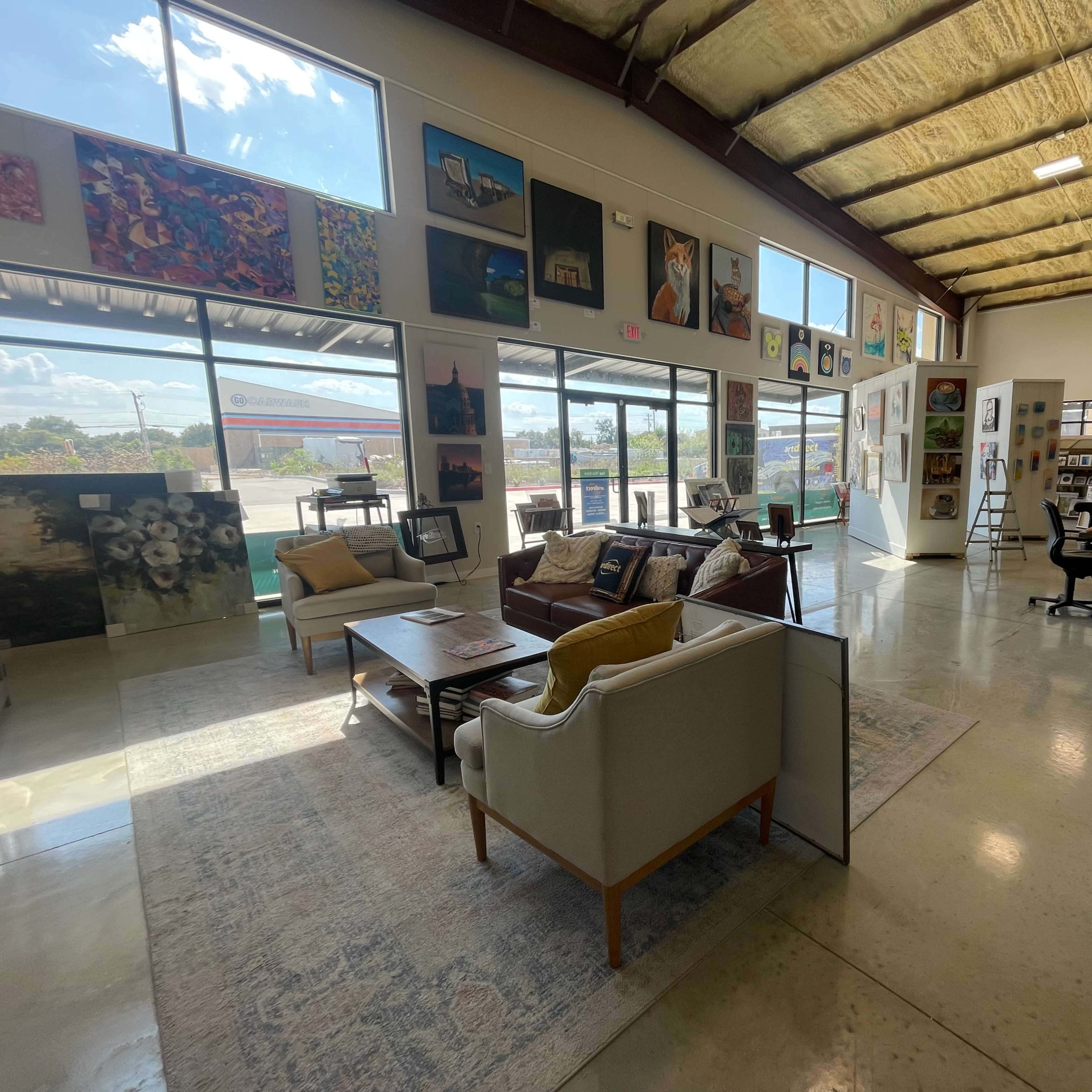 An art gallery with various paintings displayed on the walls and furniture arranged in a spacious interior.