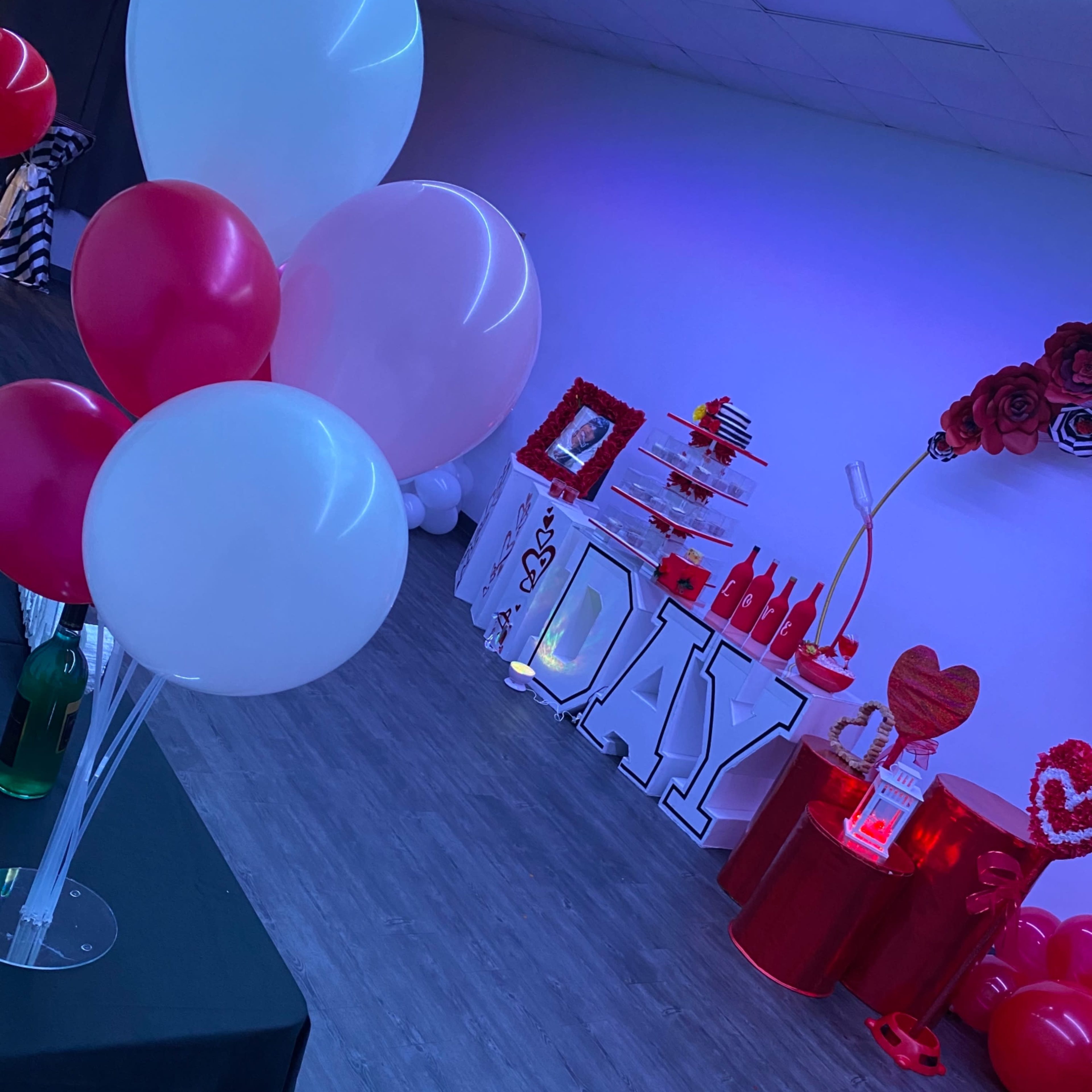 A decorated event space with red and white balloons, a large "VALENTINE'S DAY" display, and festive decorations on tables.