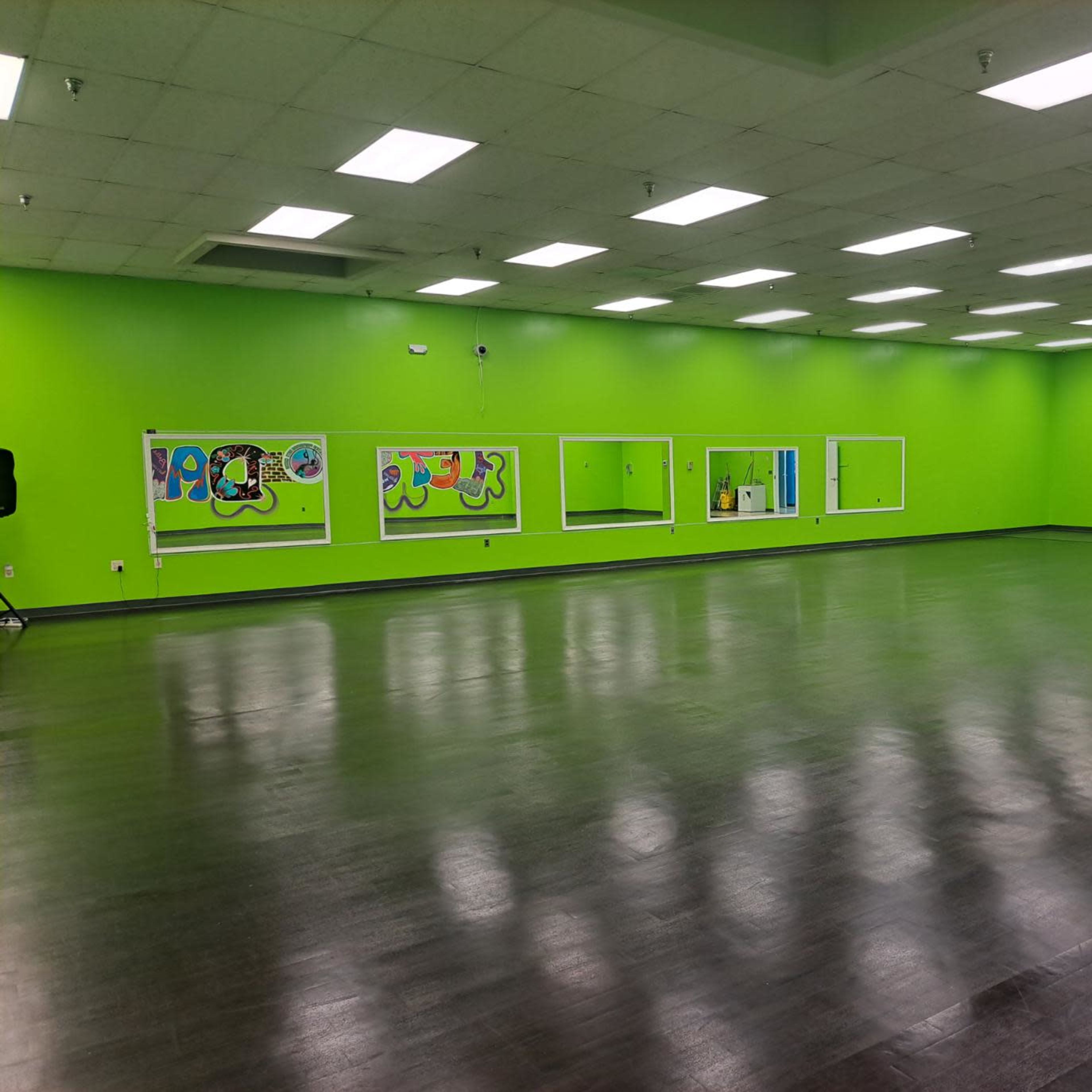 A large, empty room with bright green walls and several mirrors along one side.