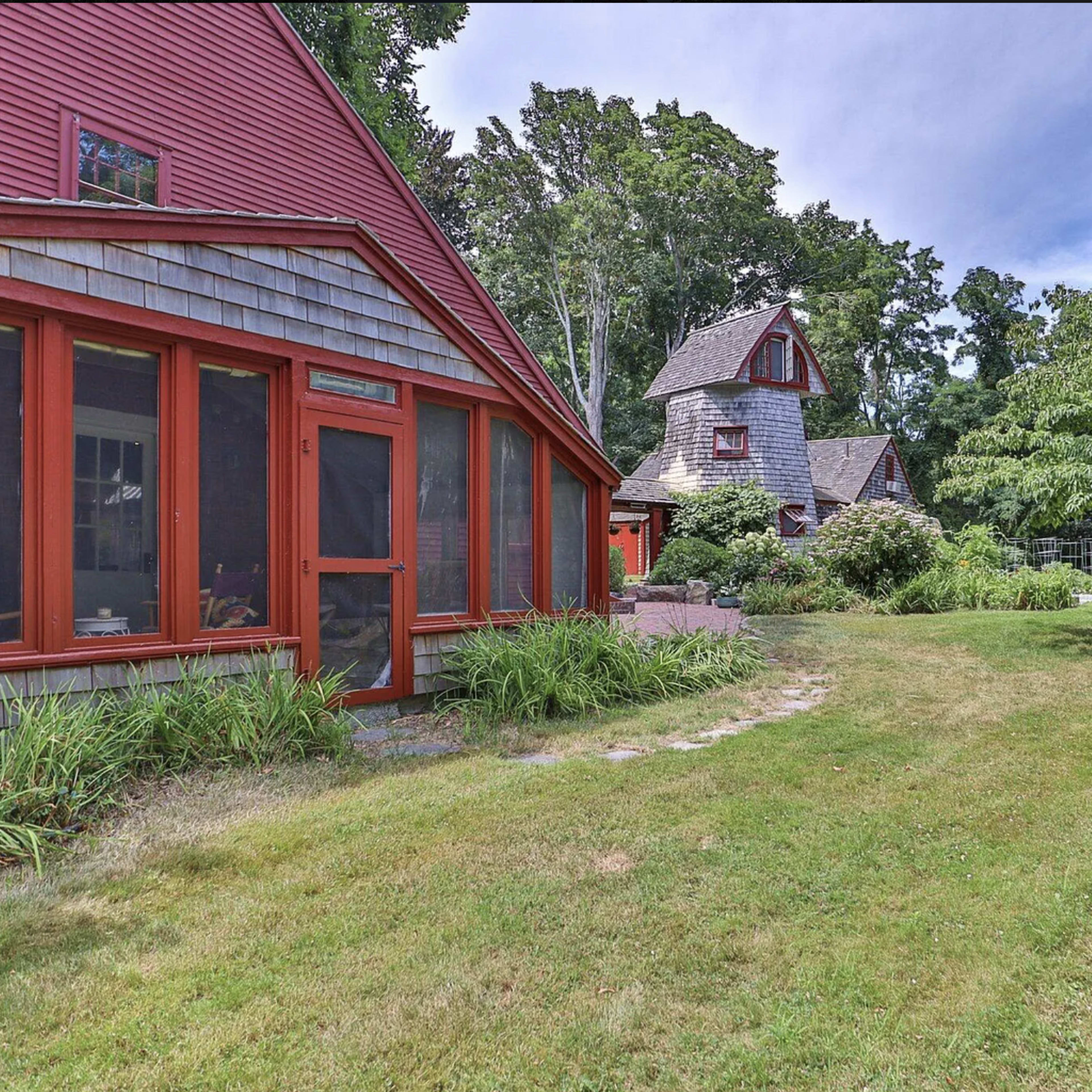 A yard with a landscaped garden featuring two distinct red-roofed buildings surrounded by greenery.