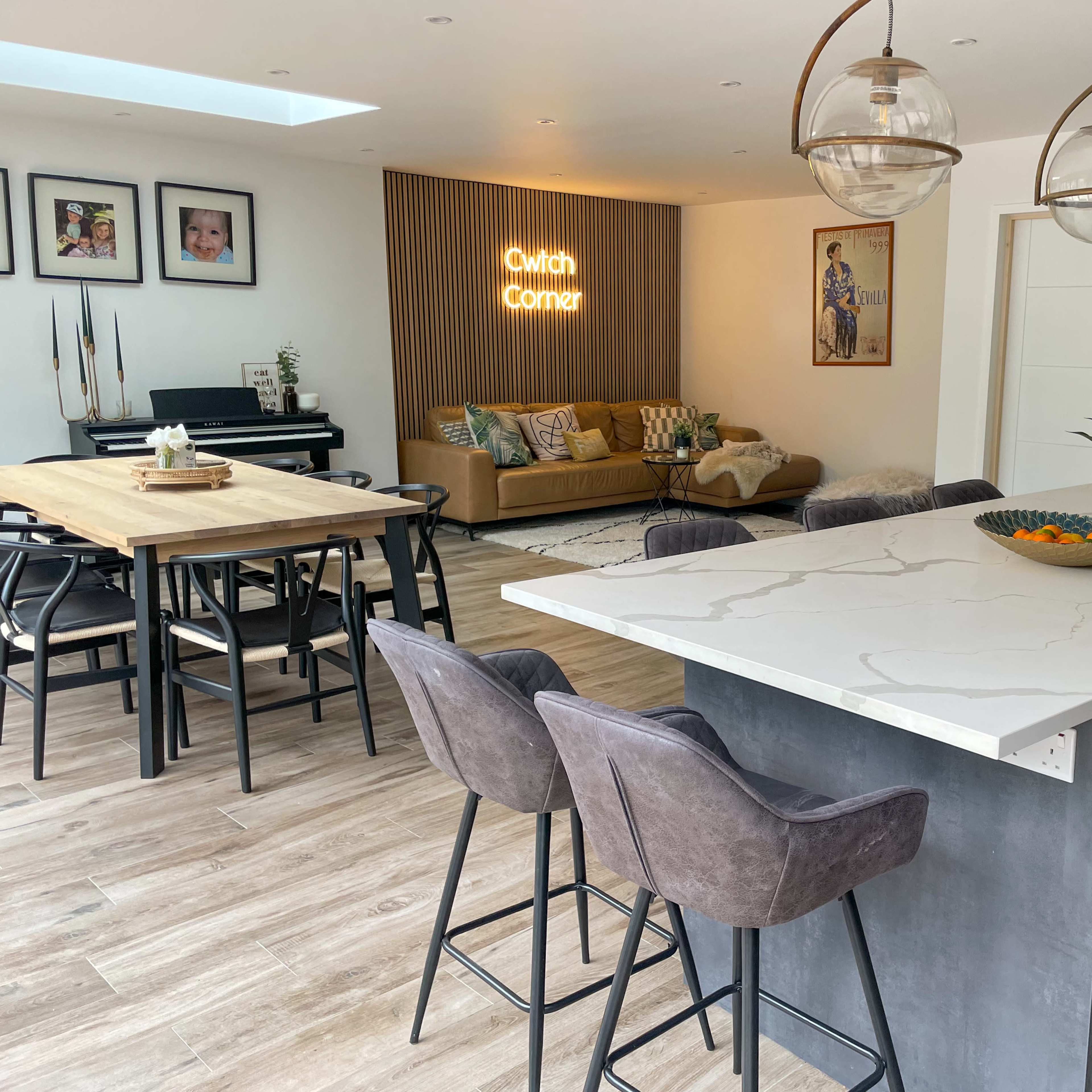 A modern open-plan living space with a kitchen island, dining table, and a cozy seating area adorned with decorative elements.