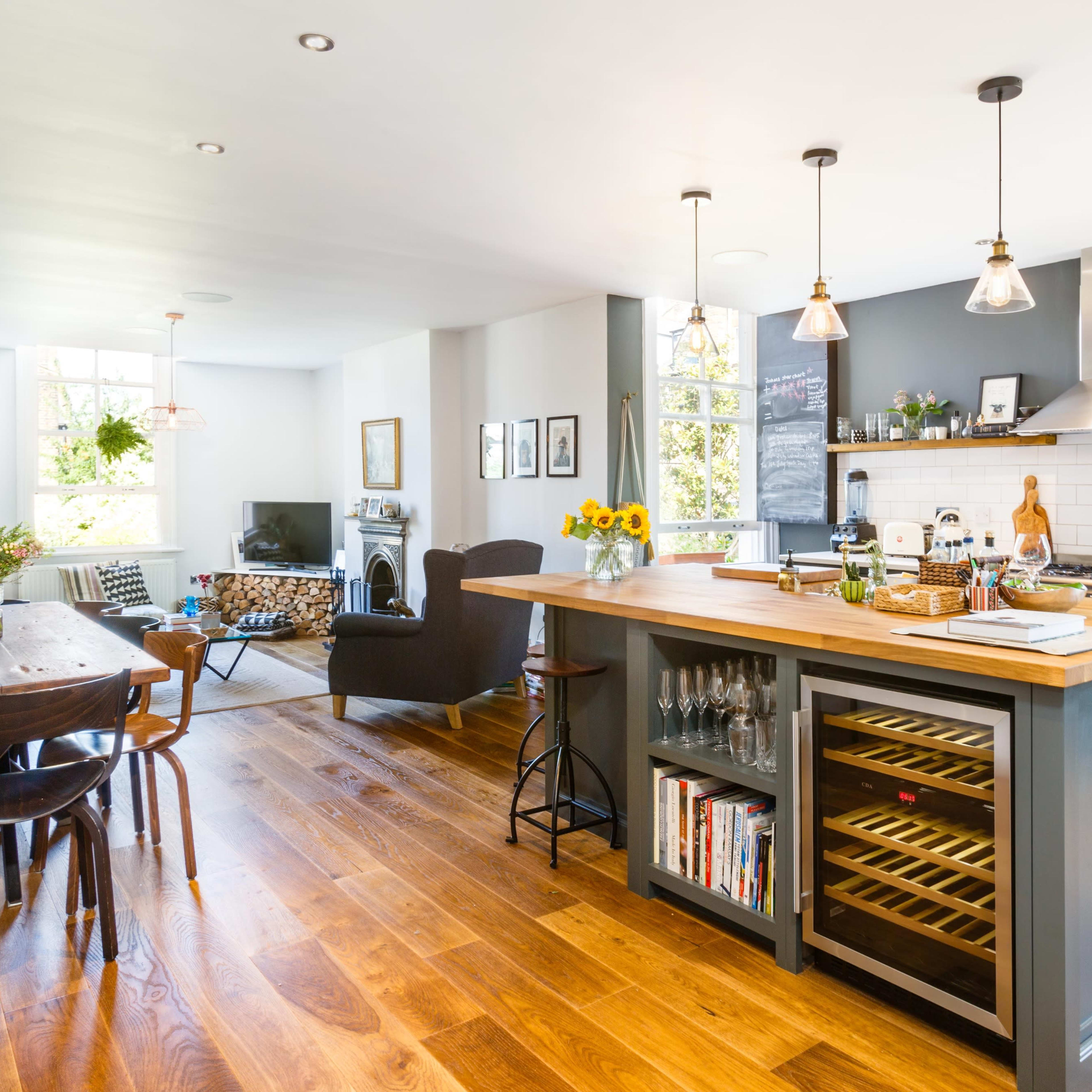 A modern open-concept kitchen and dining area features a wooden island, a dining table, and large windows that allow natural light to fill the space.