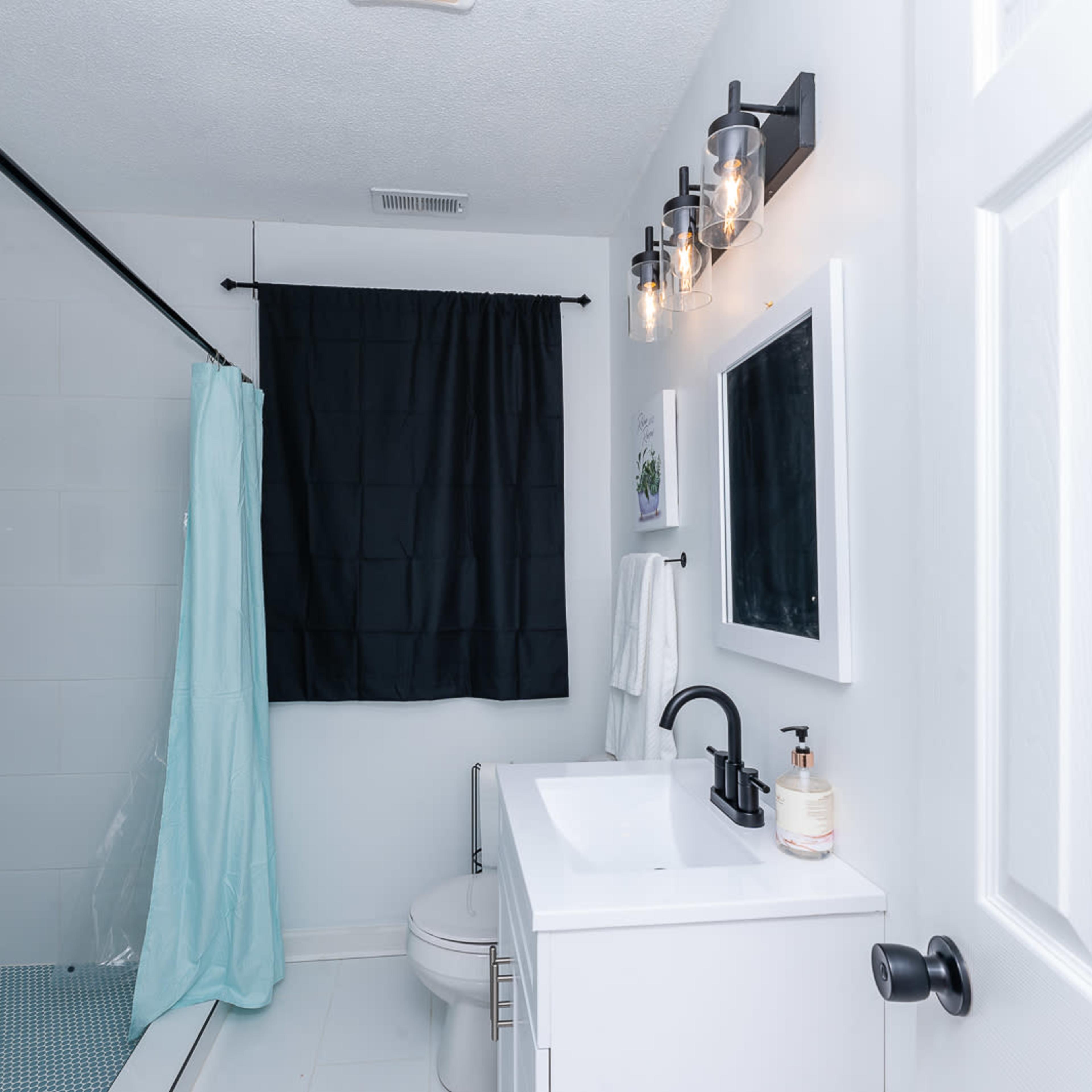 A modern bathroom featuring a shower with a glass door, a white vanity with a sink, and neutral-colored walls.