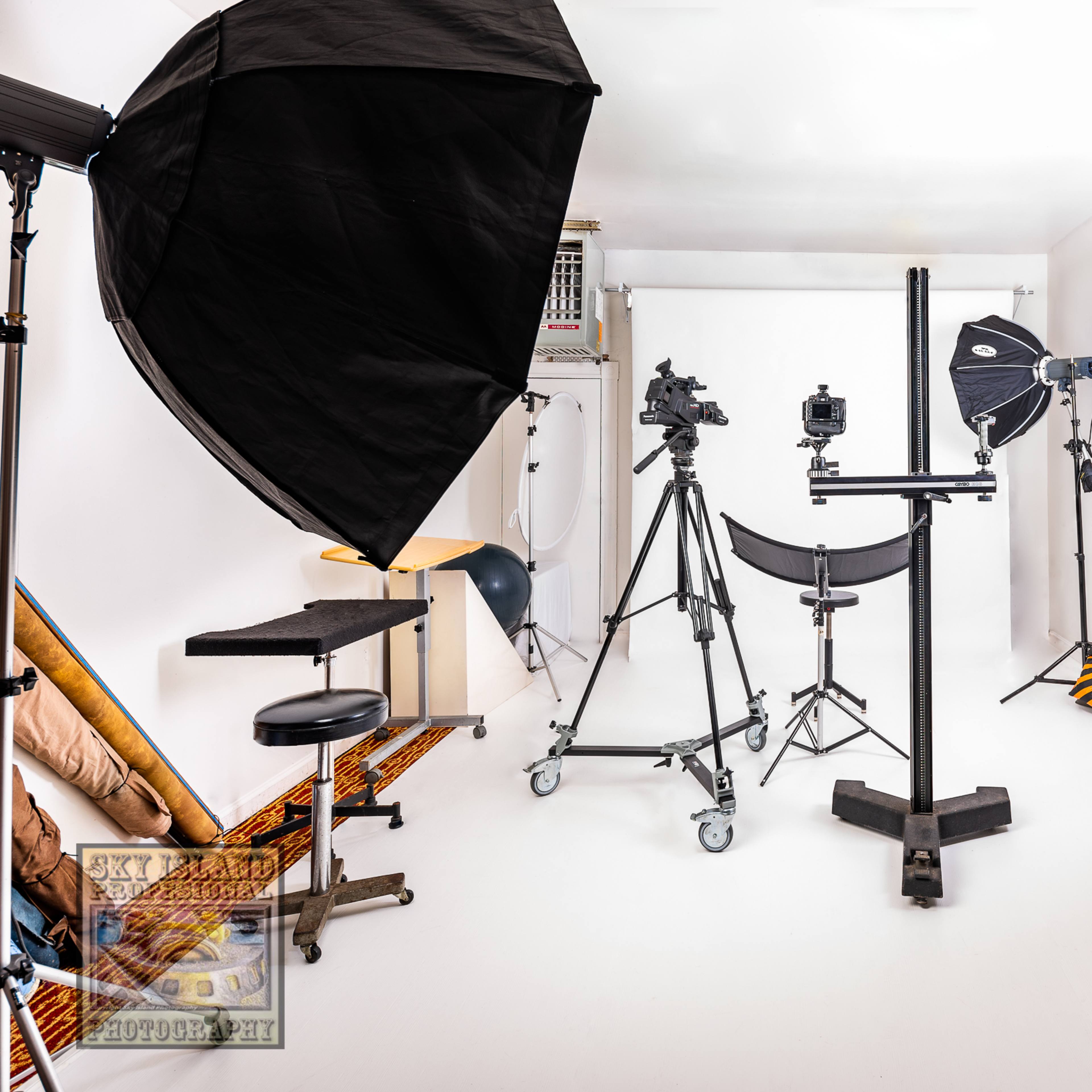 A photography studio equipped with various lighting setups and a camera on a tripod.