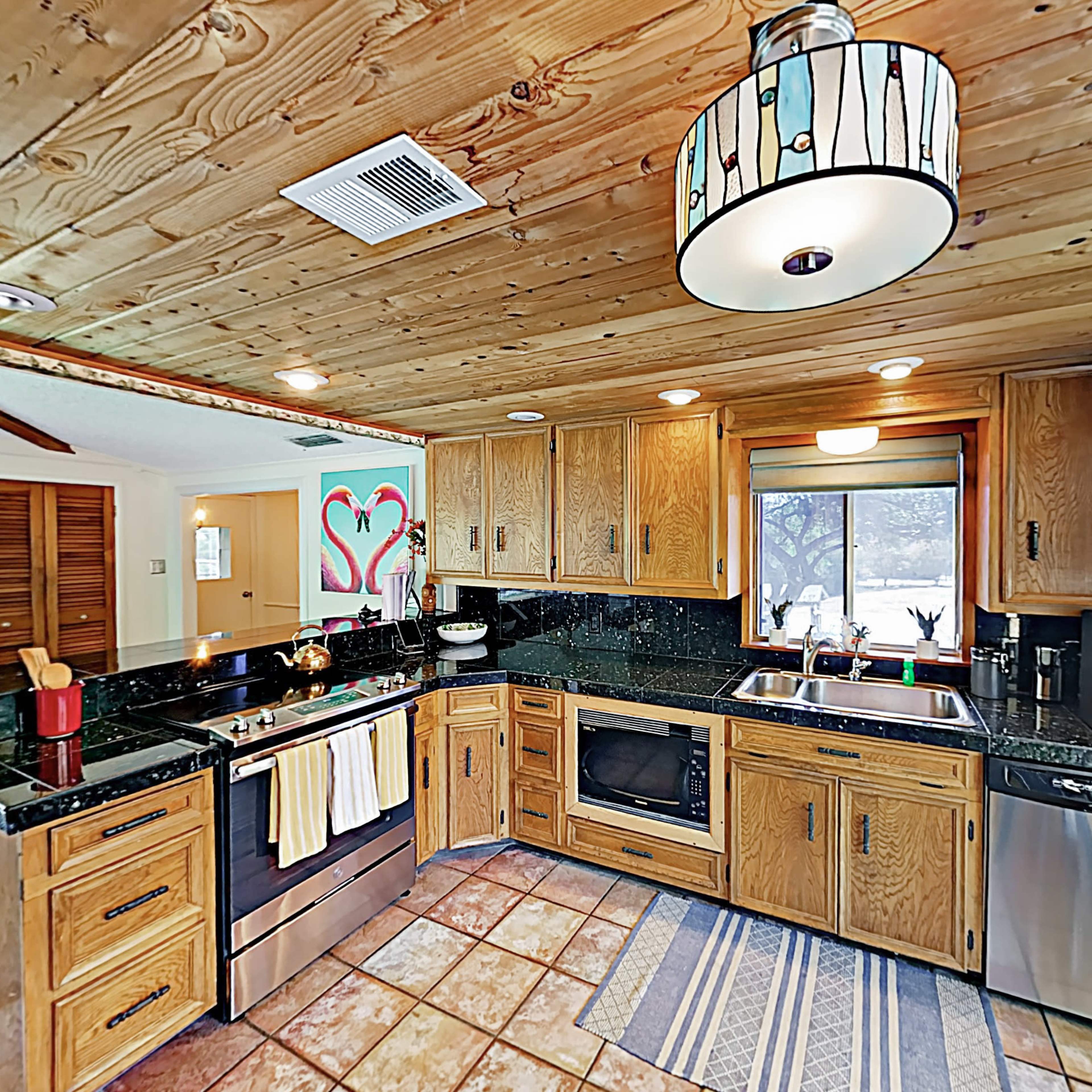 A kitchen featuring wooden cabinetry, a dark countertop, and a large window providing natural light.