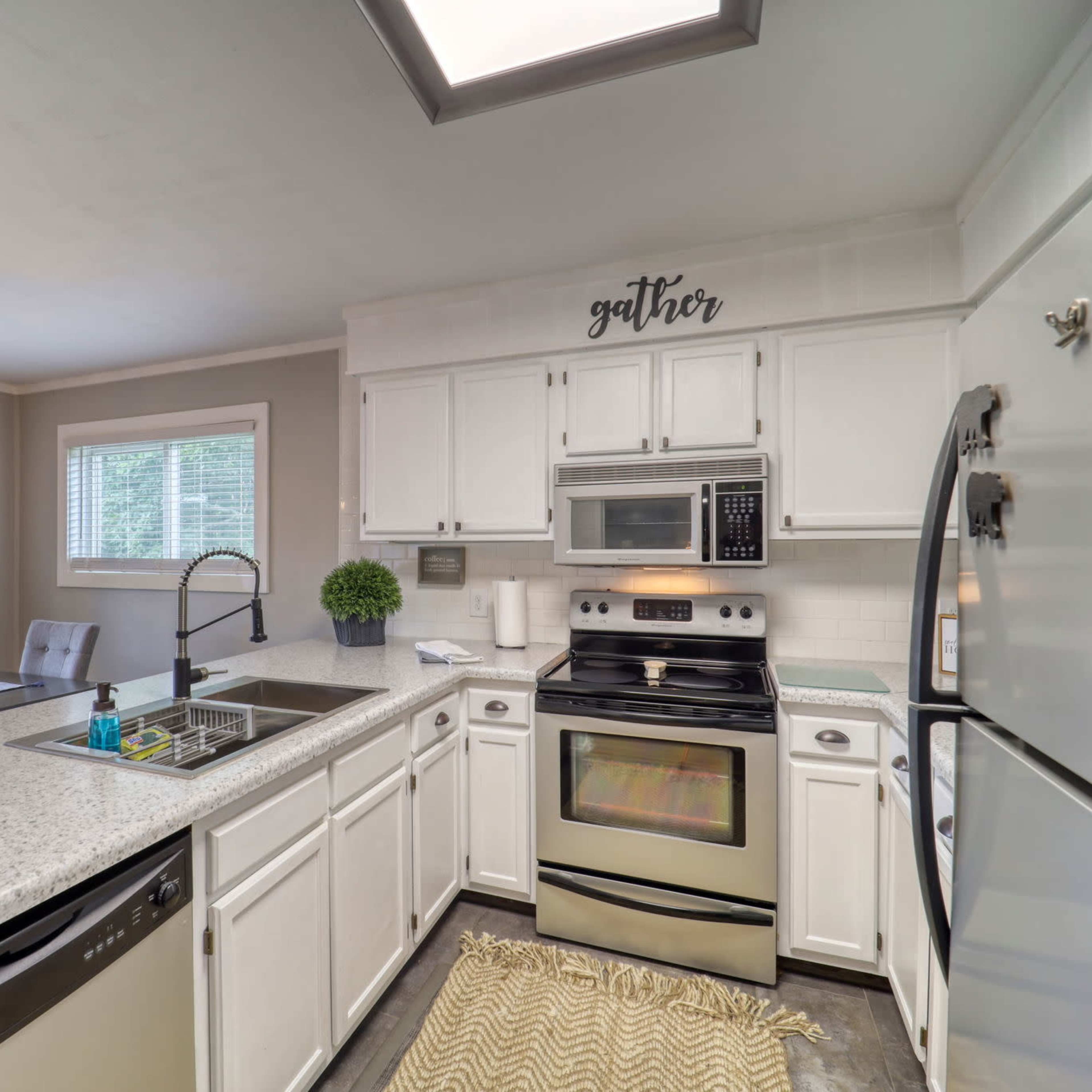 A modern kitchen features white cabinetry, stainless steel appliances, and a central island with seating.
