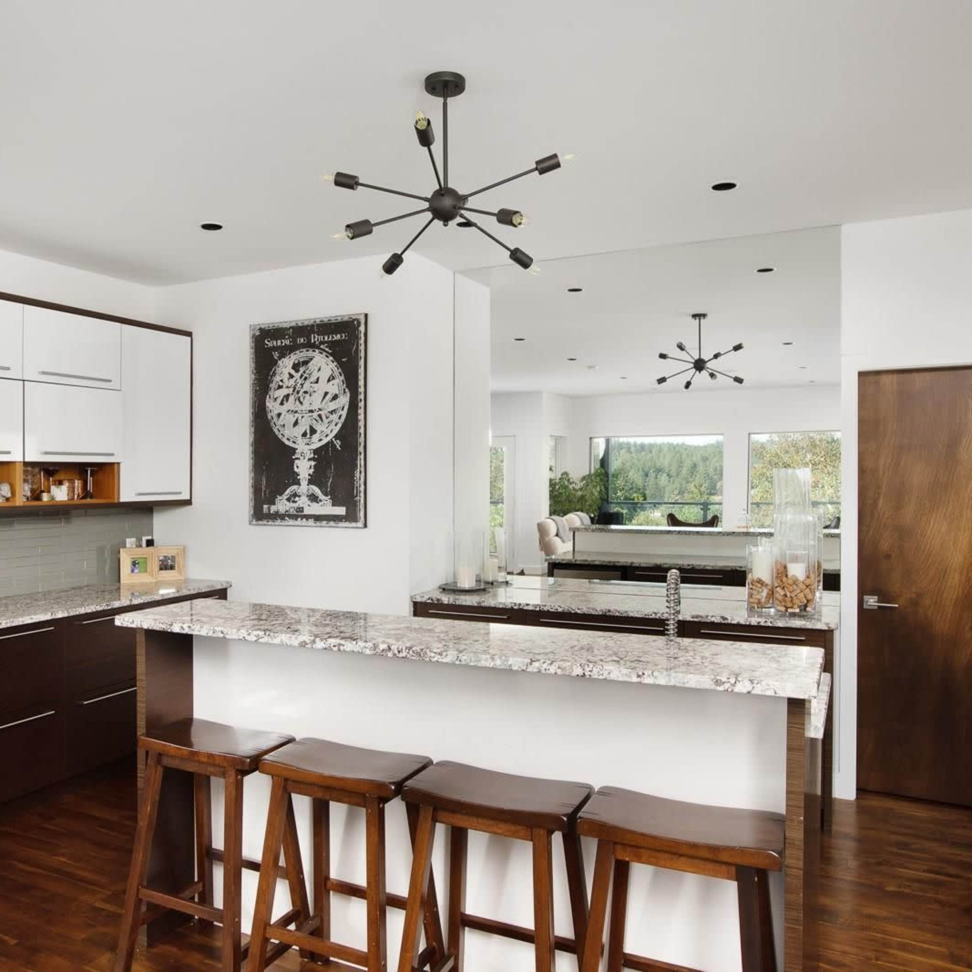 A modern kitchen with dark wood cabinets, a granite countertop, and a small dining area with bar stools.