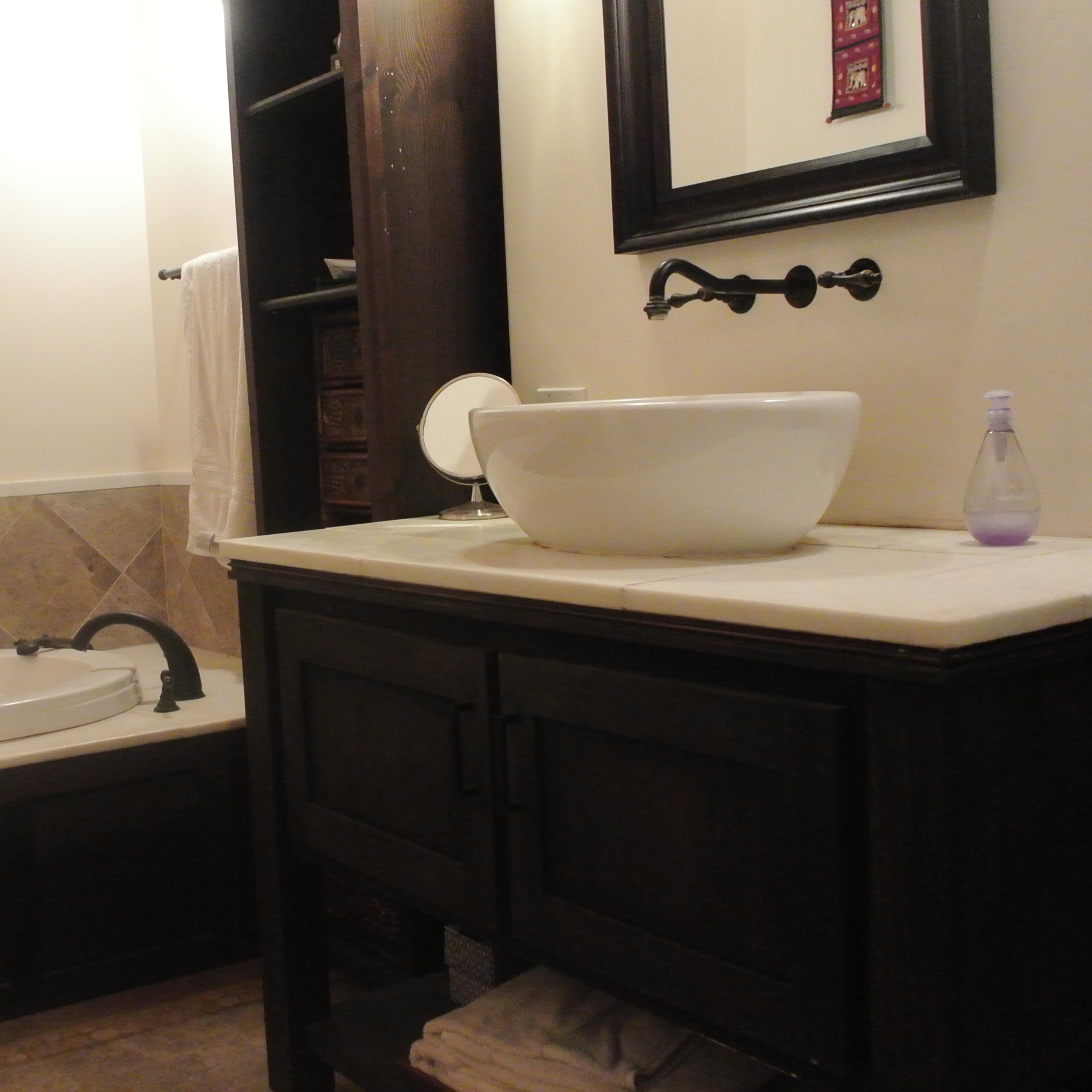 A bathroom featuring a bathtub, a sink with a countertop, and a wall-mounted mirror.