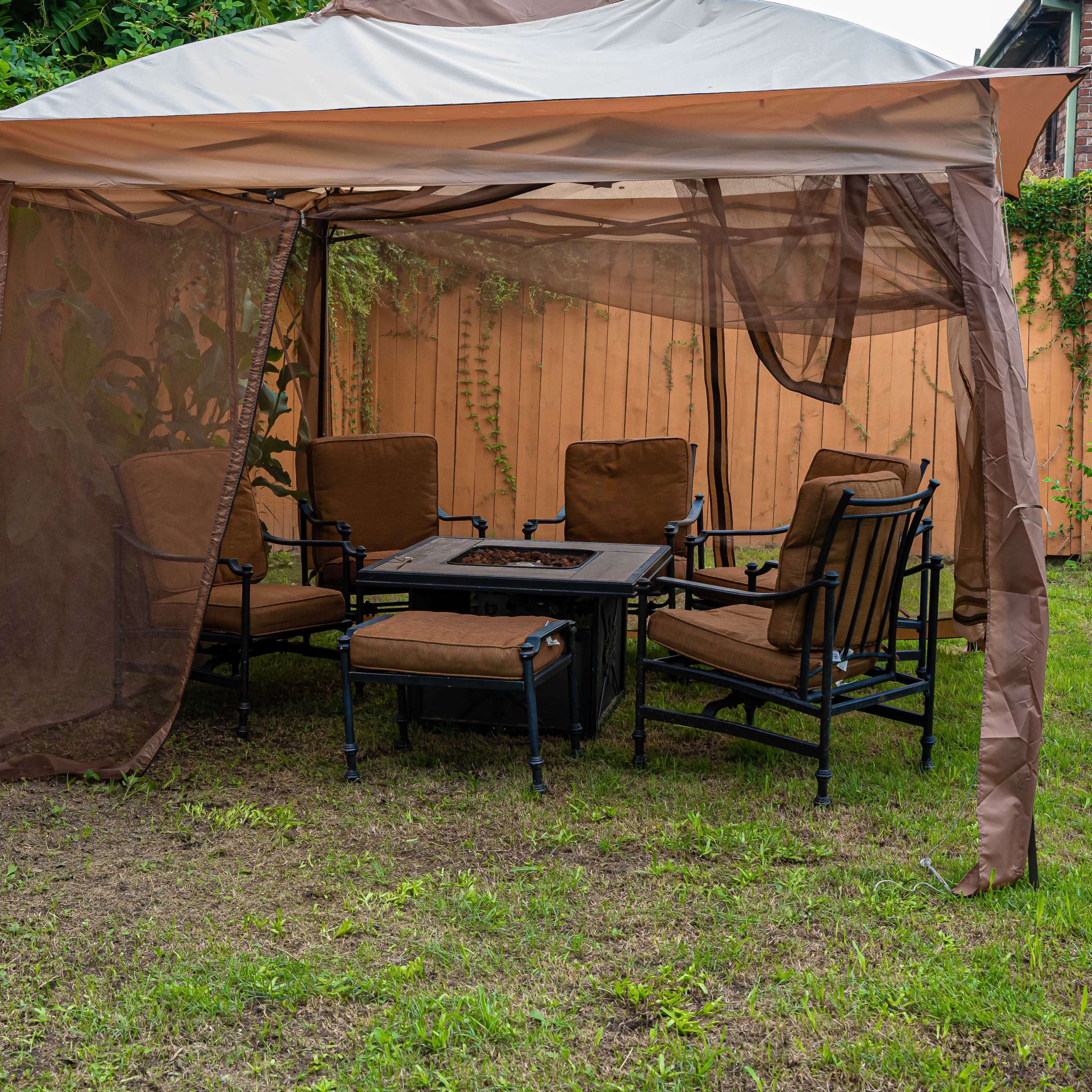 A covered outdoor seating area features a fire pit surrounded by six cushioned chairs, enclosed by mesh panels.