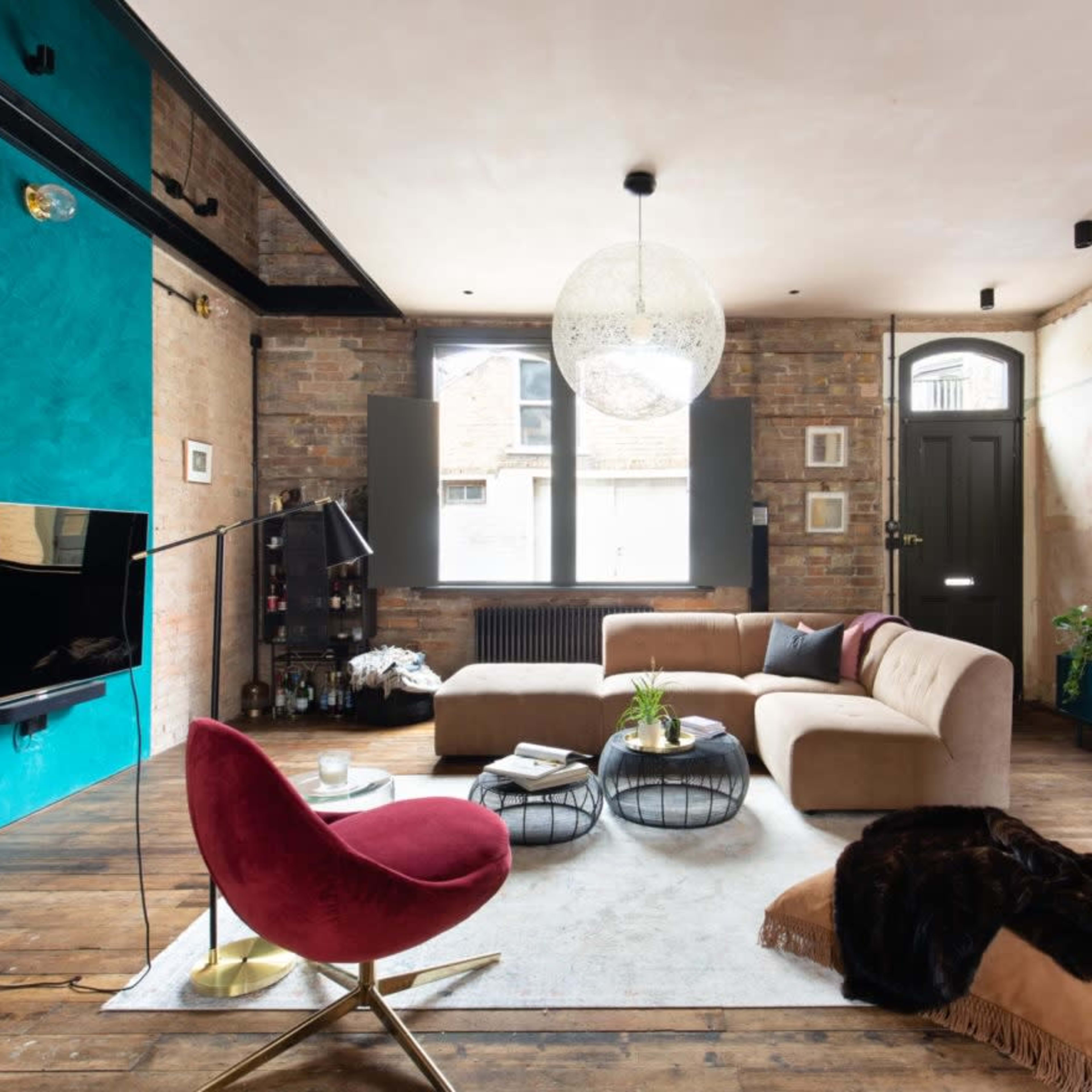 A modern living room with a brown sectional sofa, a circular coffee table, a large round mirror, and a blue accent wall.