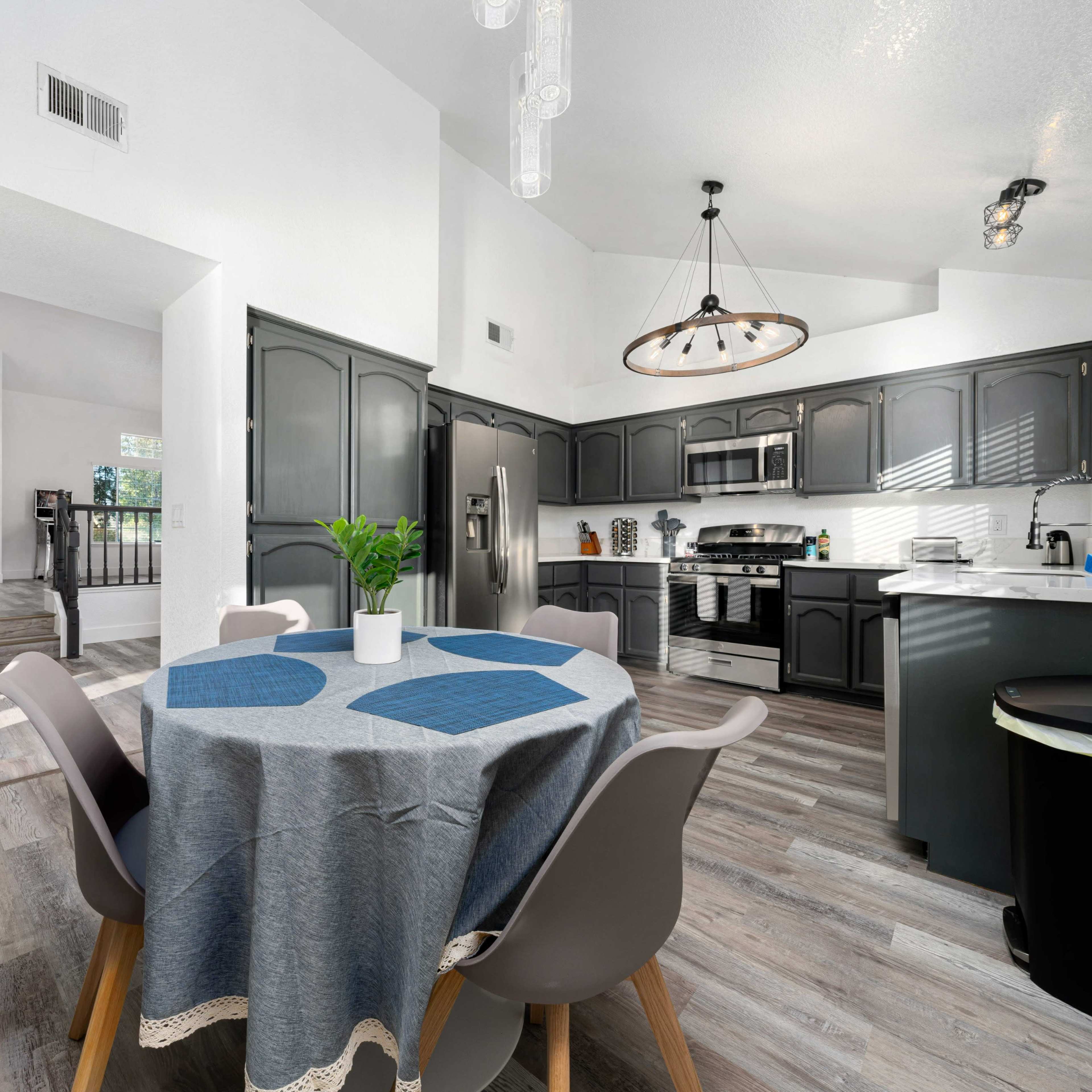 A modern kitchen and dining area with a round table, gray cabinetry, and stainless steel appliances.