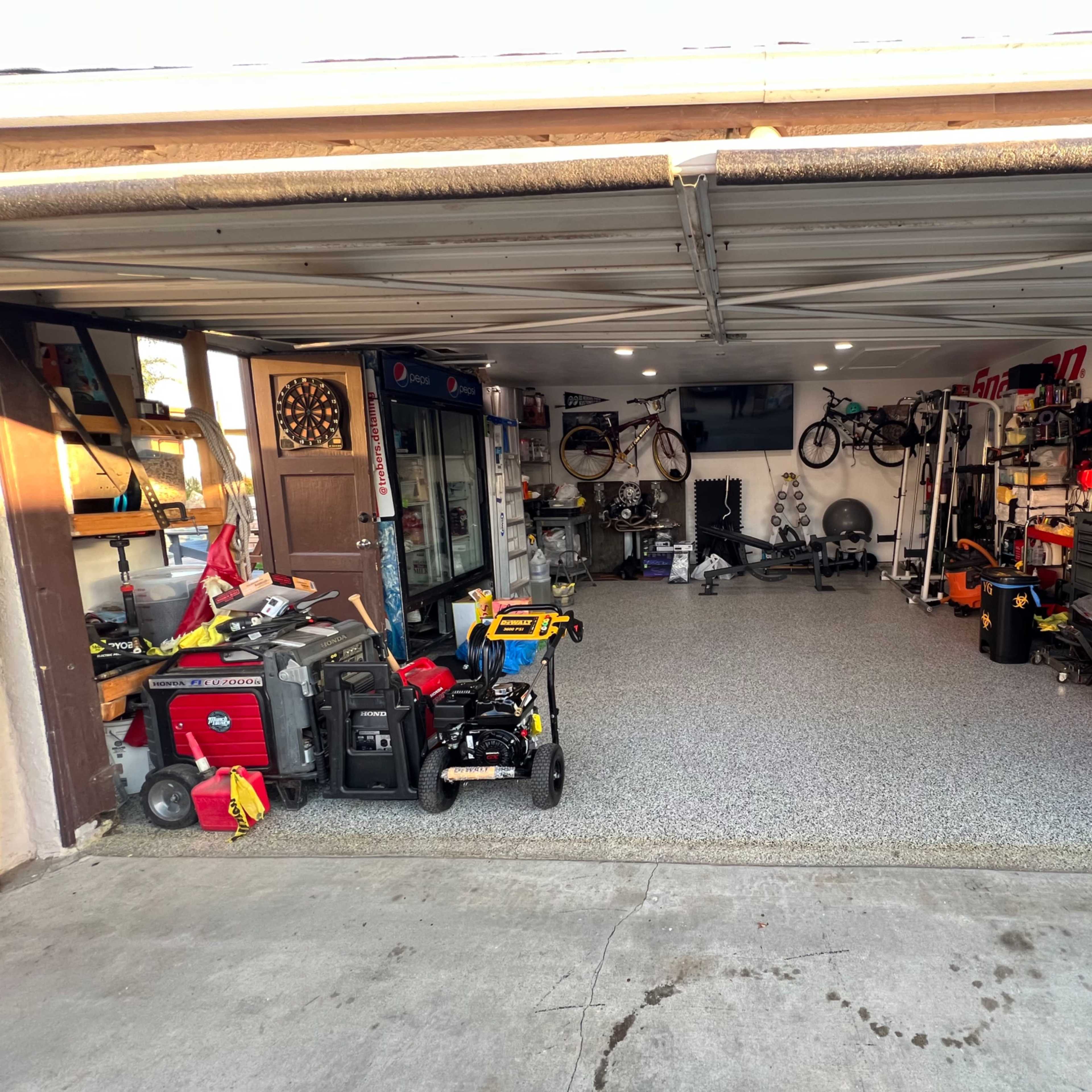 A spacious garage organized with tools, equipment, and bikes arranged along the walls.