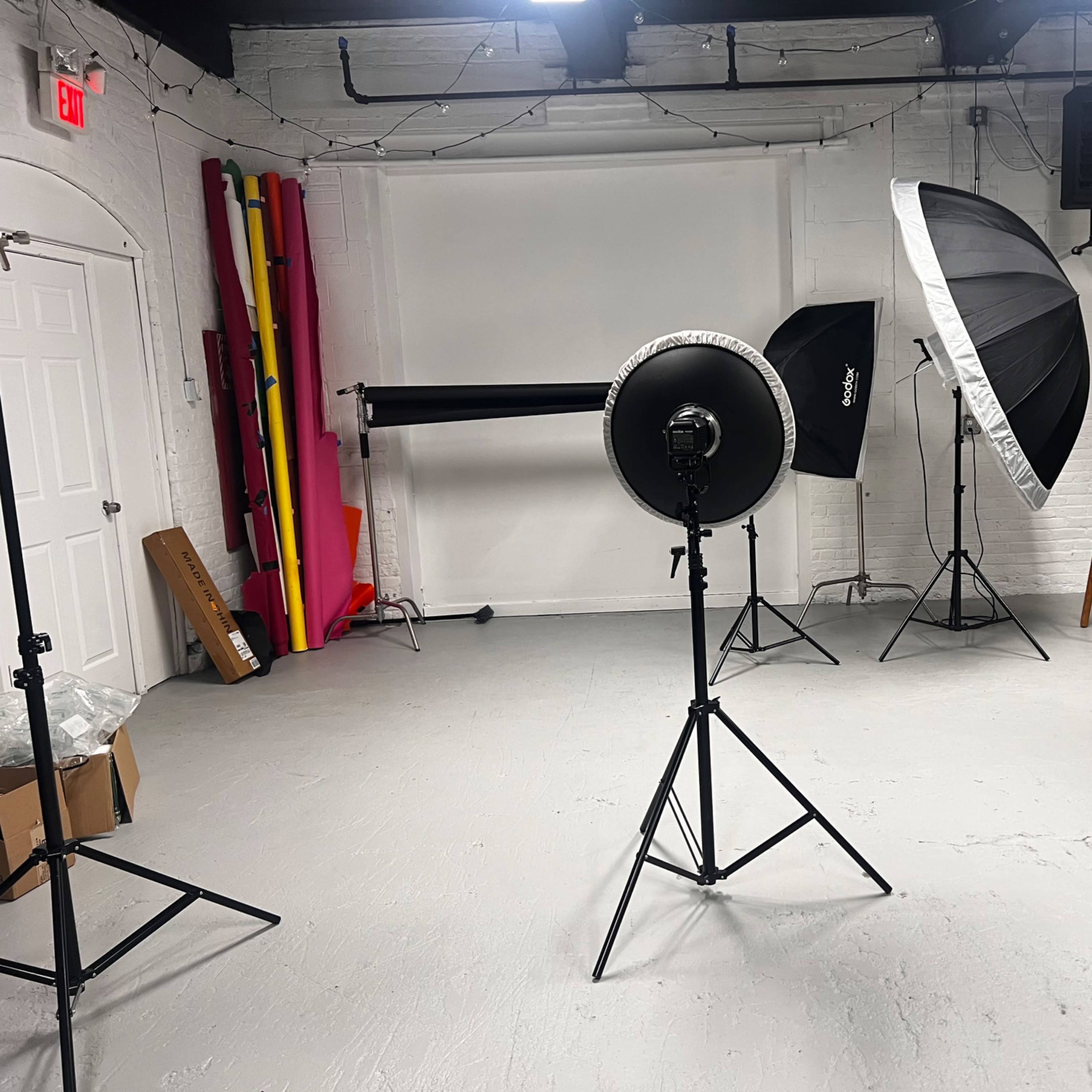A photography studio setup with various lighting equipment and backdrops arranged in the space.