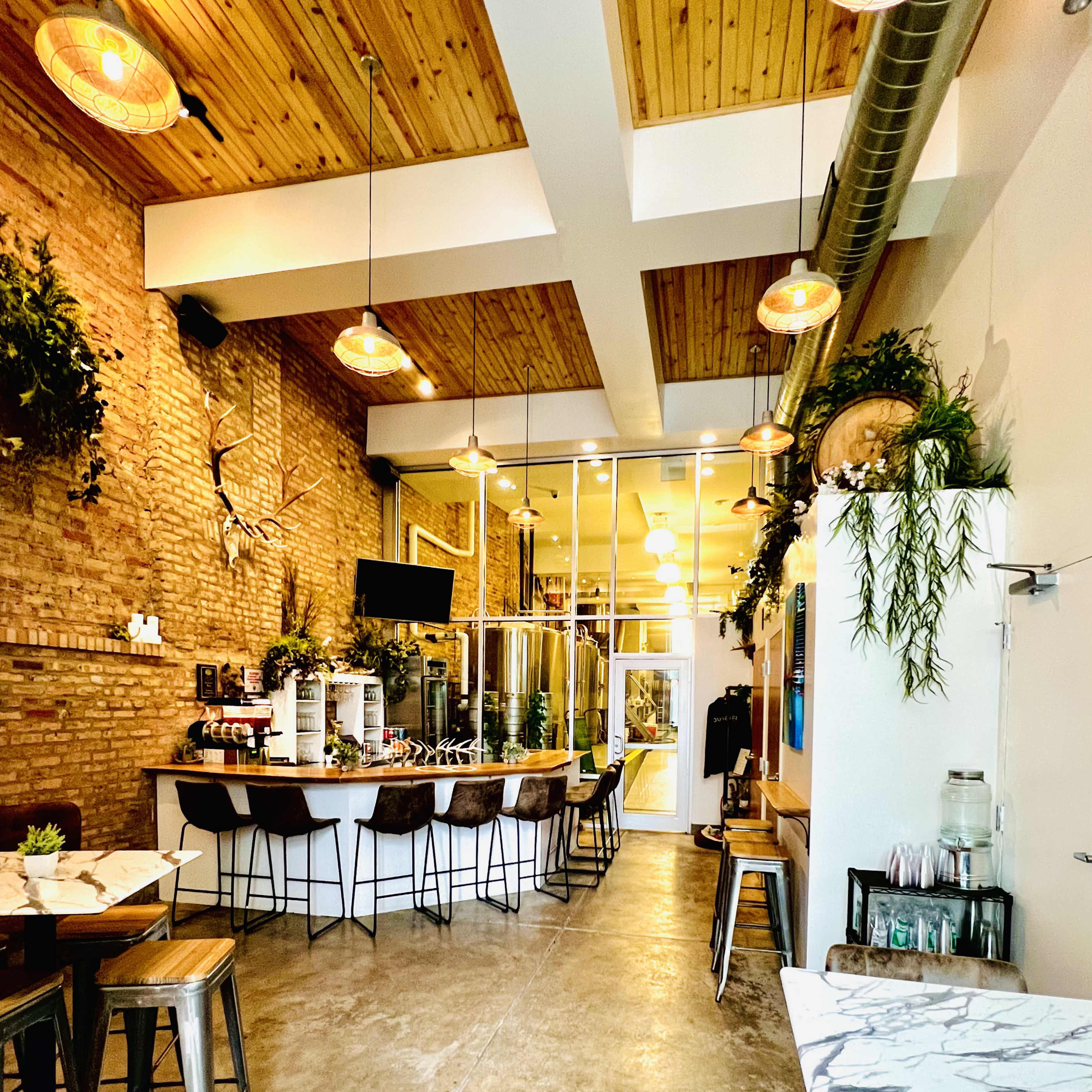 A modern café interior with wooden beams, a bar area, and tables arranged along a polished concrete floor.
