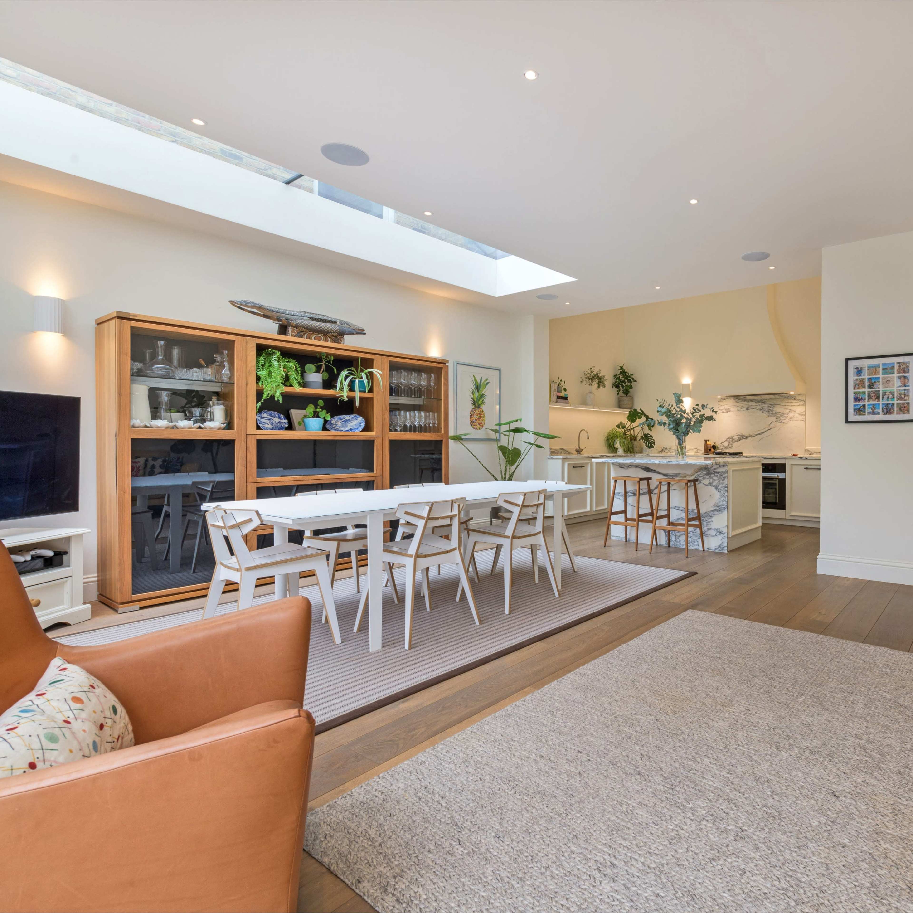 A bright and spacious open-plan living area featuring a dining table, a kitchen, and a cozy seating arrangement.