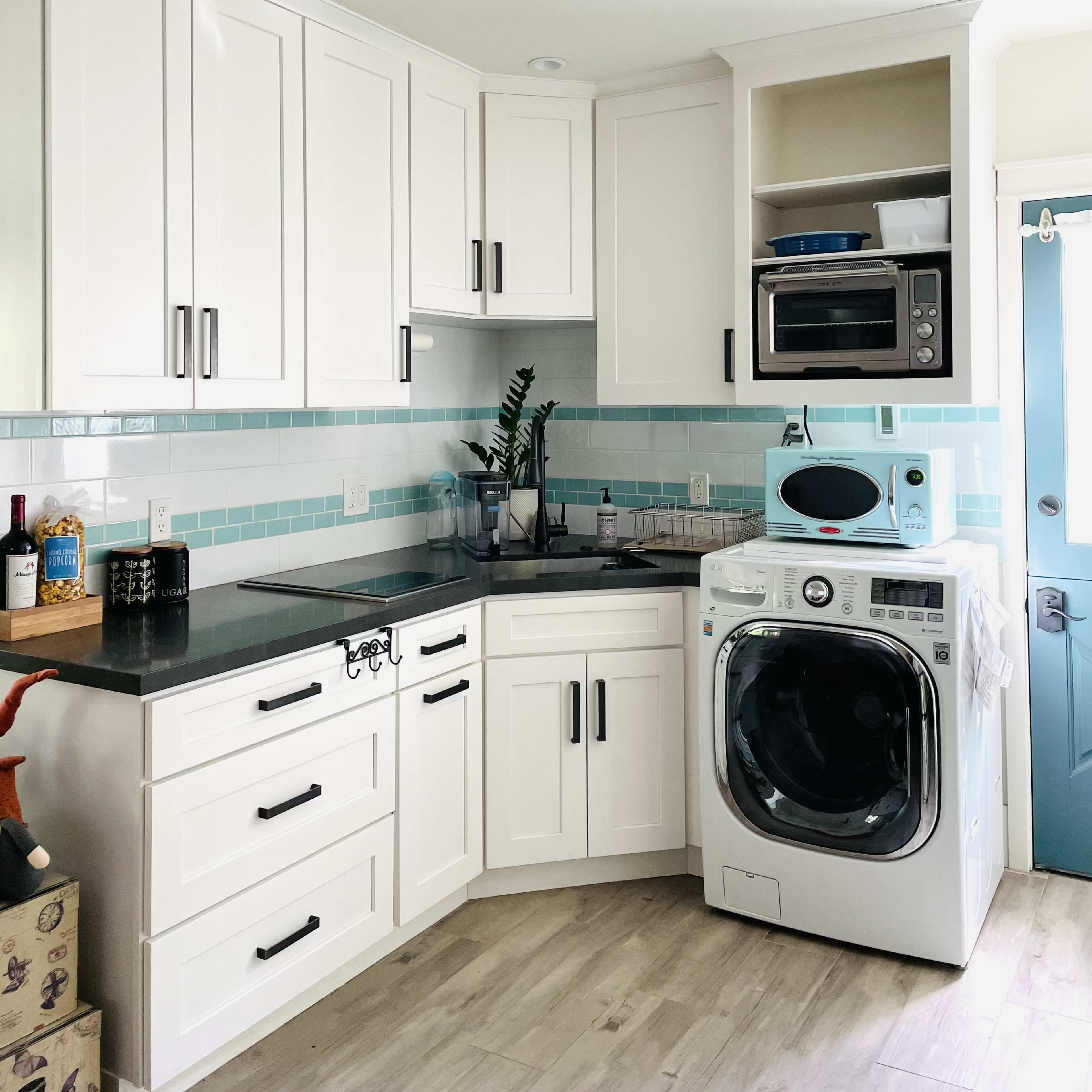 A modern kitchen with white cabinetry, a built-in microwave, and a washing machine integrated into the design.