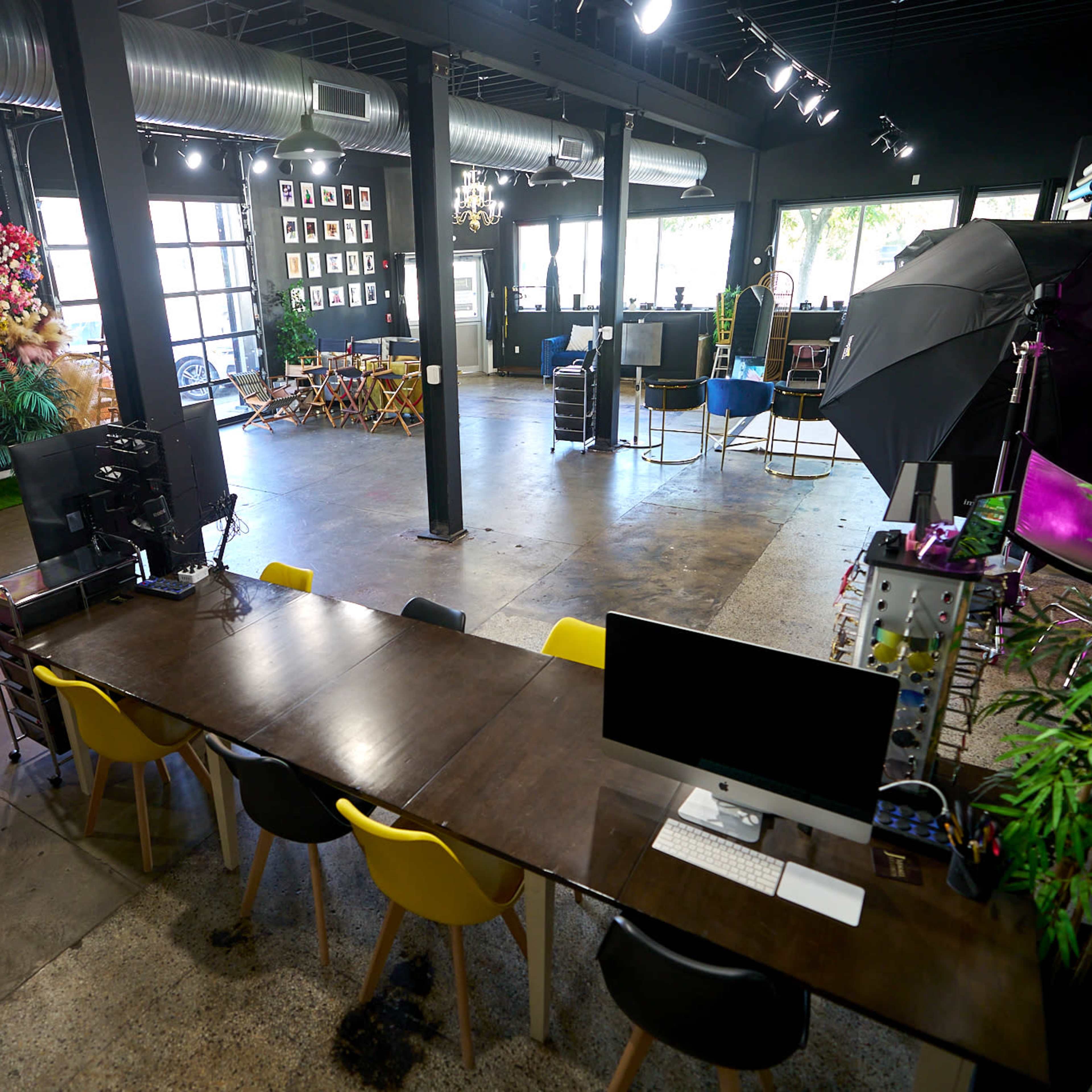 An interior space with a large table surrounded by colorful chairs, a floral backdrop, and various furniture setups for events or meetings.