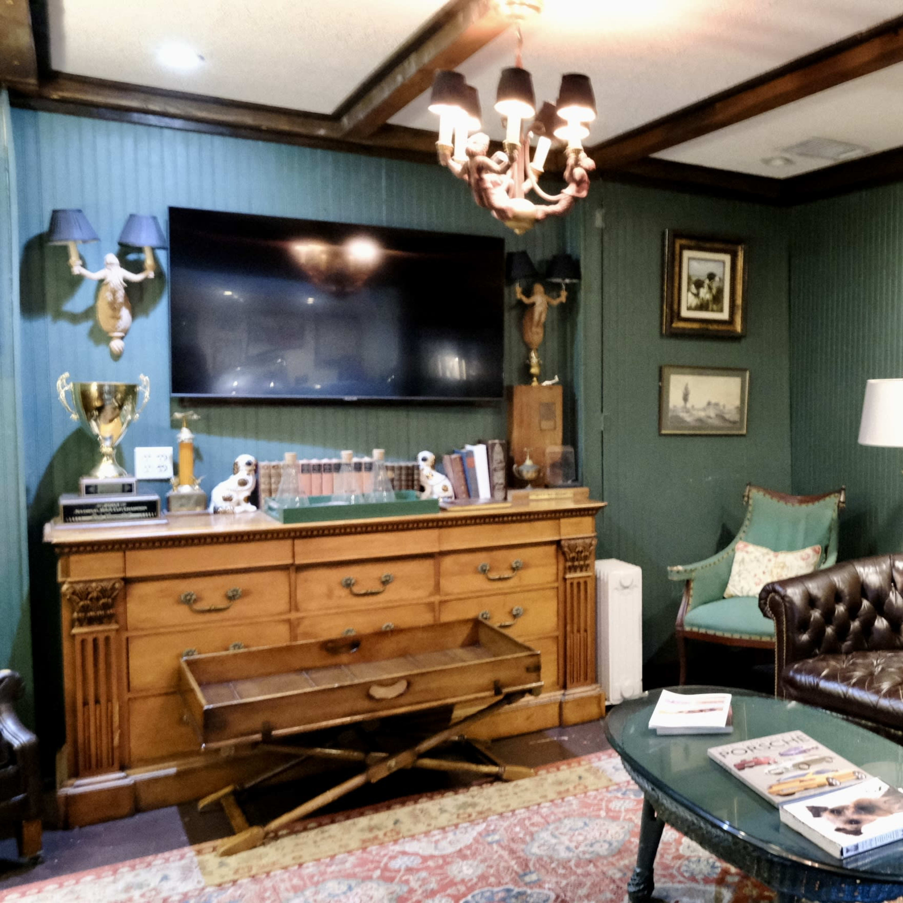 A cozy living room featuring a leather sofa, wooden furniture, a mounted television, and a large mural of a man on a horse.