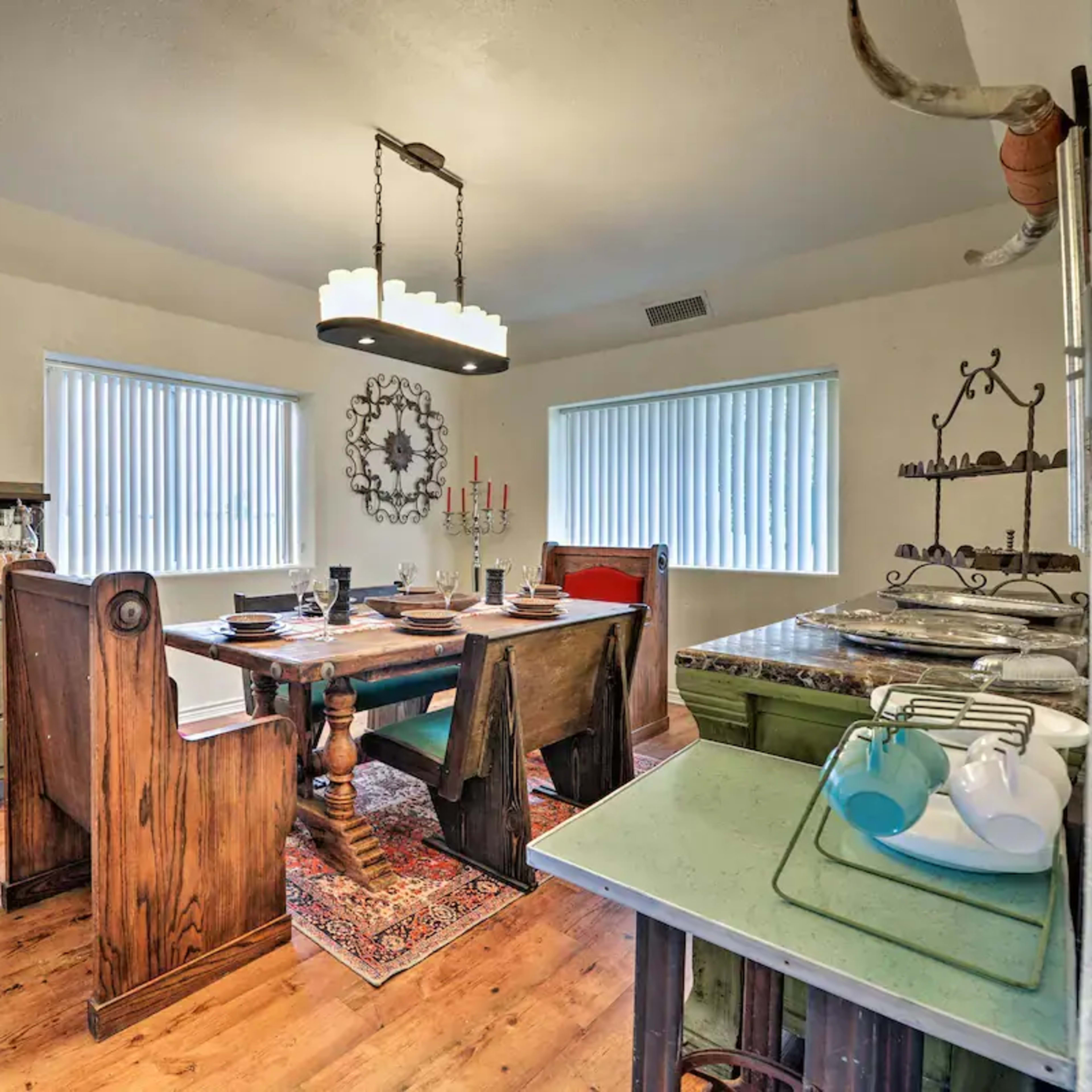 A well-furnished dining room featuring a wooden table, several chairs, and a sideboard, all complemented by large windows and decorative elements on the walls.