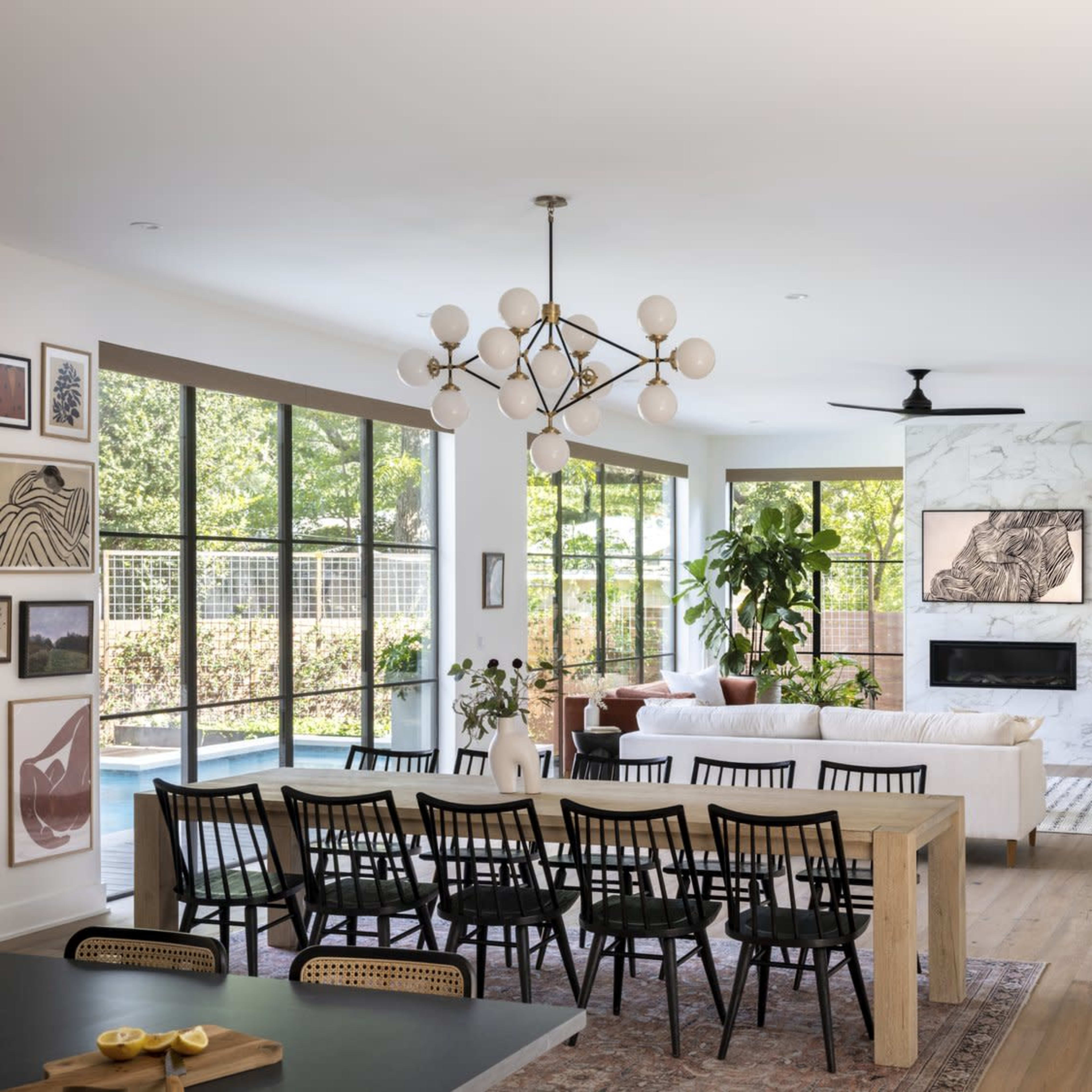 A spacious, modern living area features a white sofa, dining table, and large windows overlooking a patio.