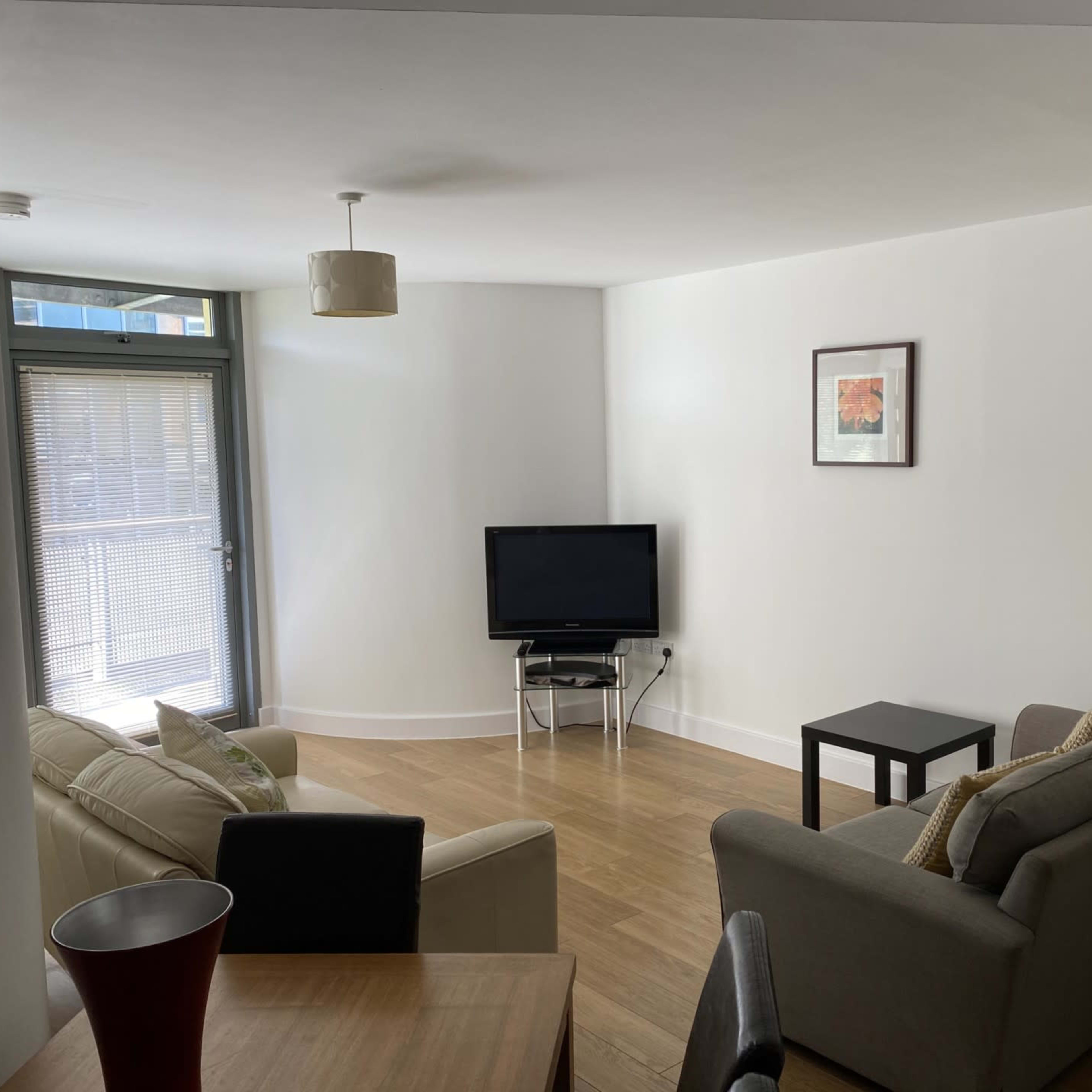 A modern, minimalist living room with two sofas, a coffee table, a television, and light-colored walls.