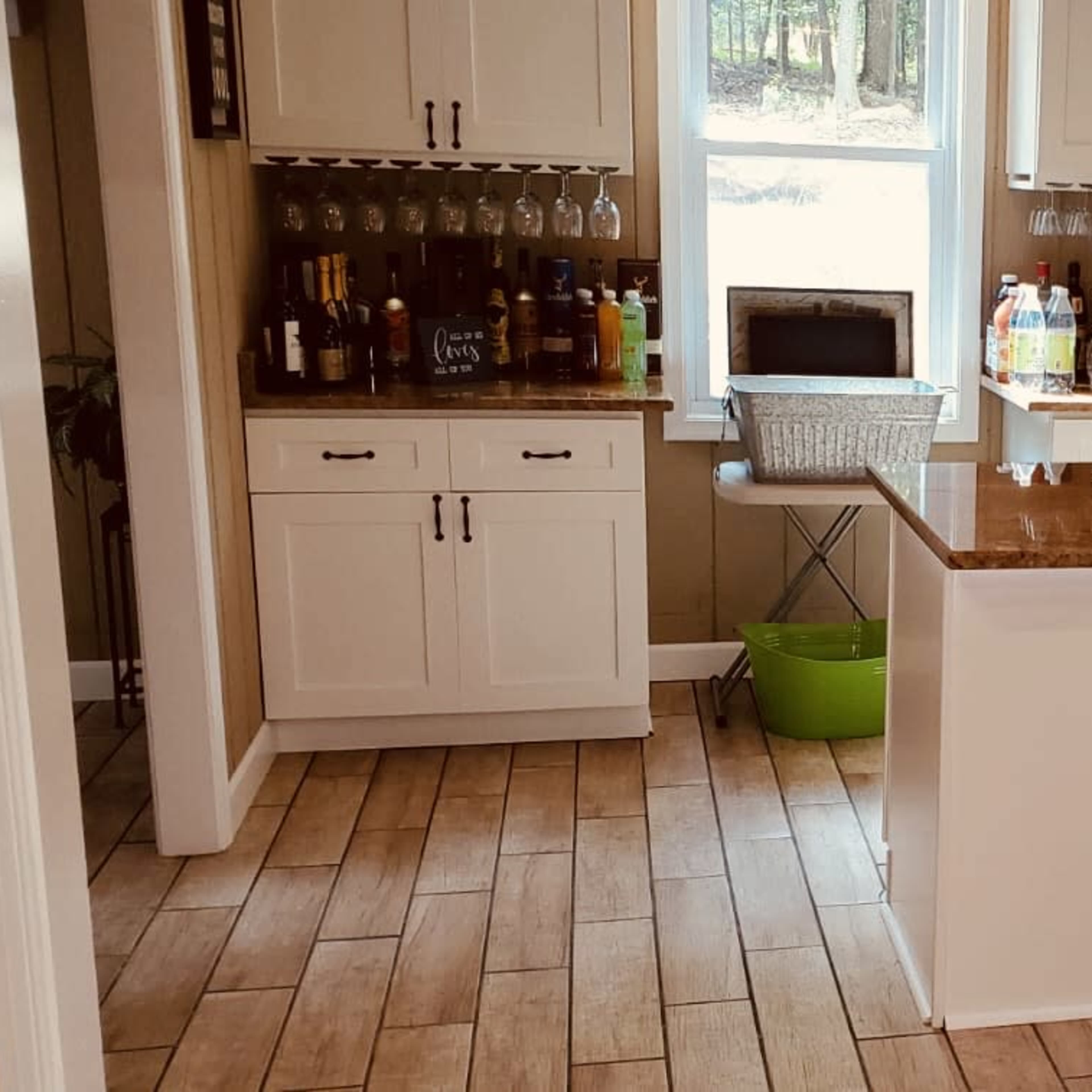 A home bar area with a central island and cabinets, surrounded by various bottles and glassware.