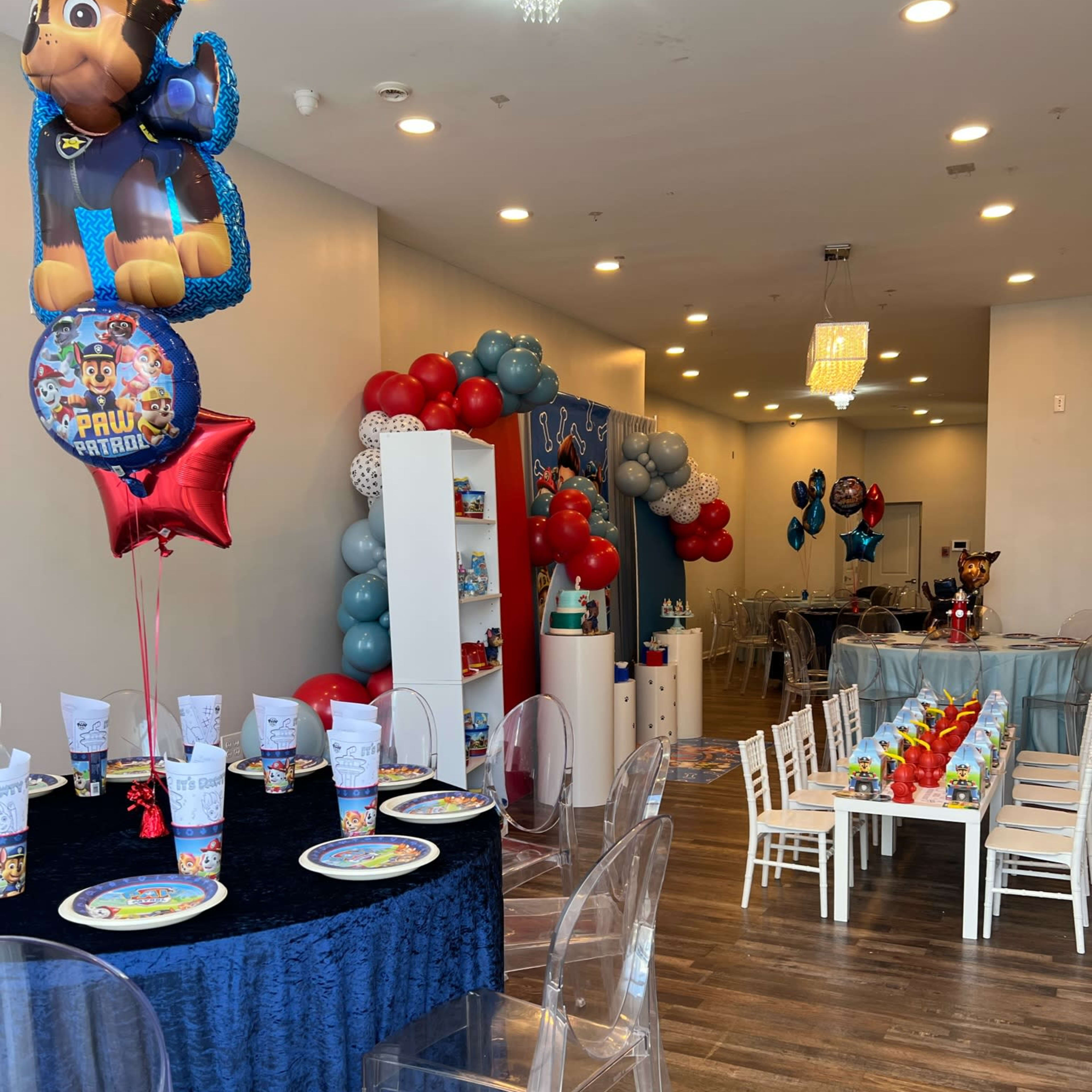 A brightly decorated party space with a table set for children's celebrations, featuring themed tableware and colorful balloons.