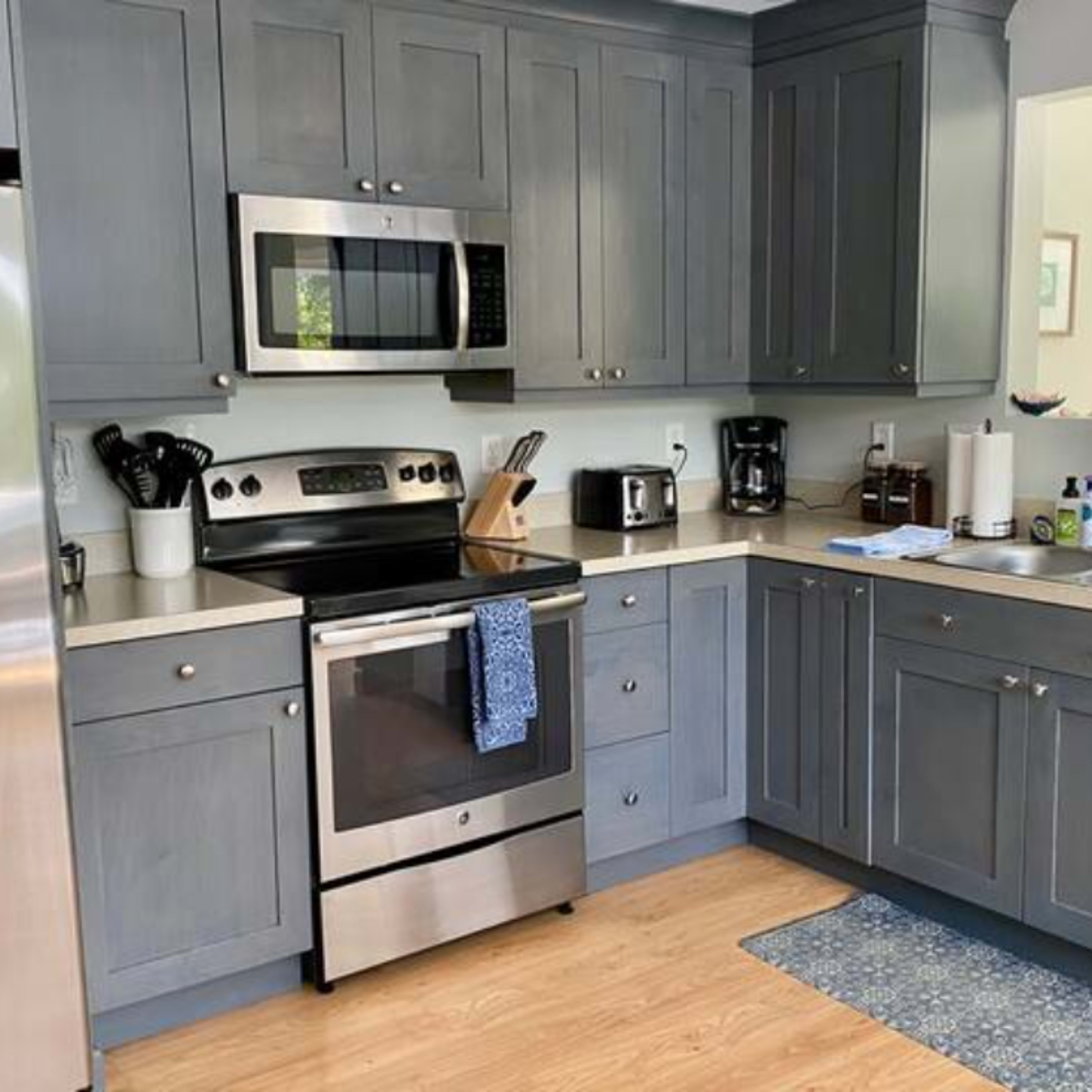 A modern kitchen features gray cabinetry, stainless steel appliances, and a countertop with various small appliances and utensils.