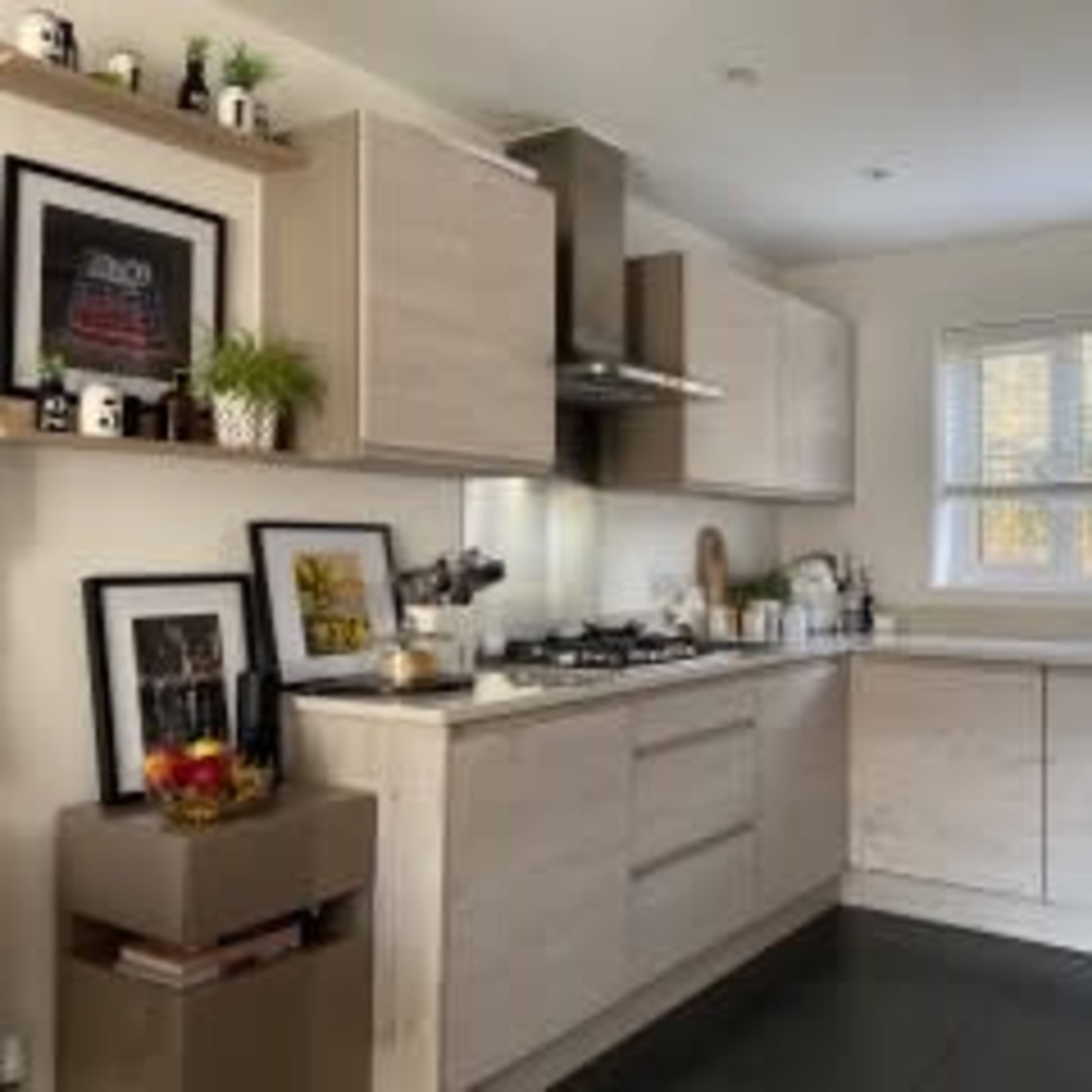 A modern kitchen features light cabinetry, a gas stove, and a window illuminating the workspaces.