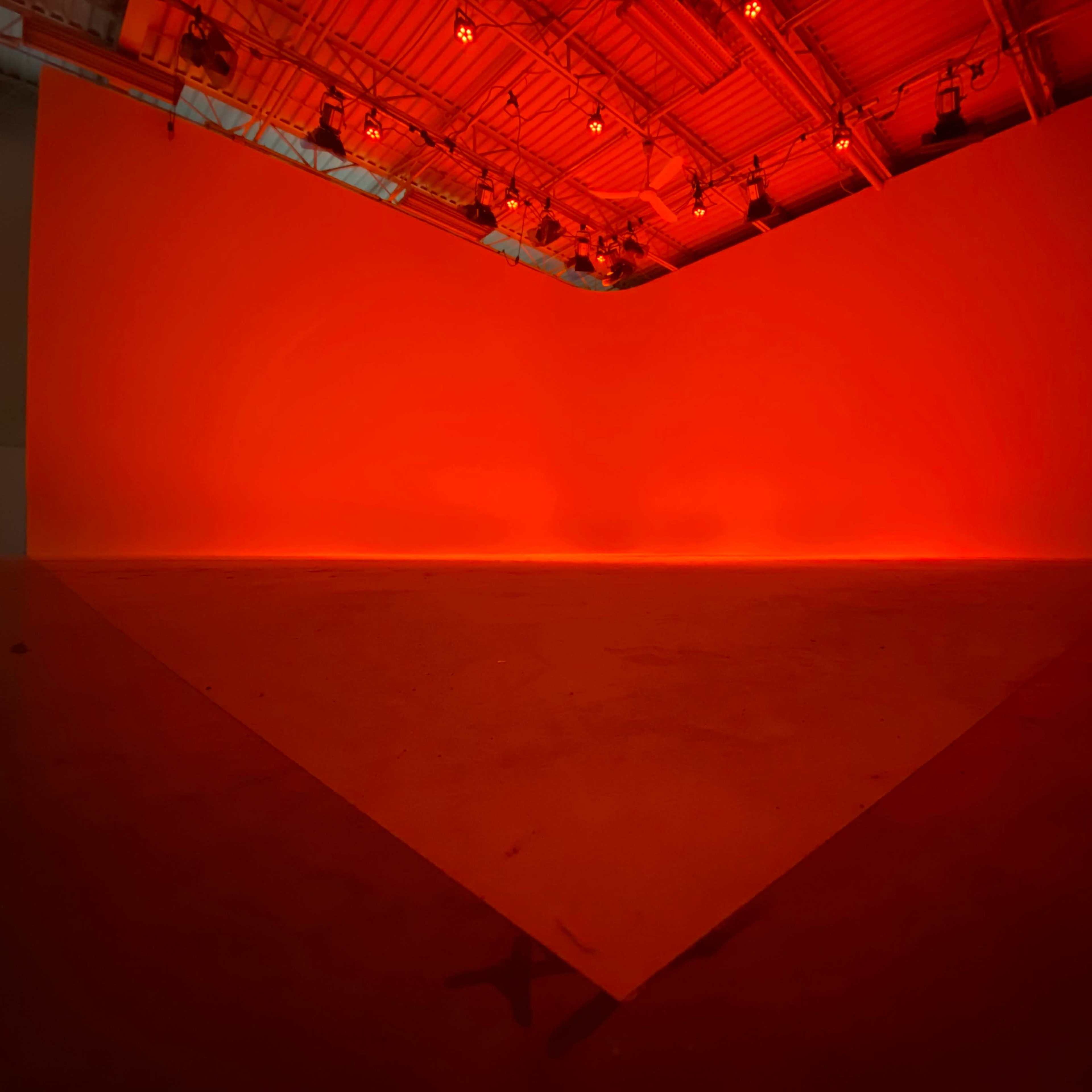 A large, empty space with a triangular lighted area and red-colored walls.