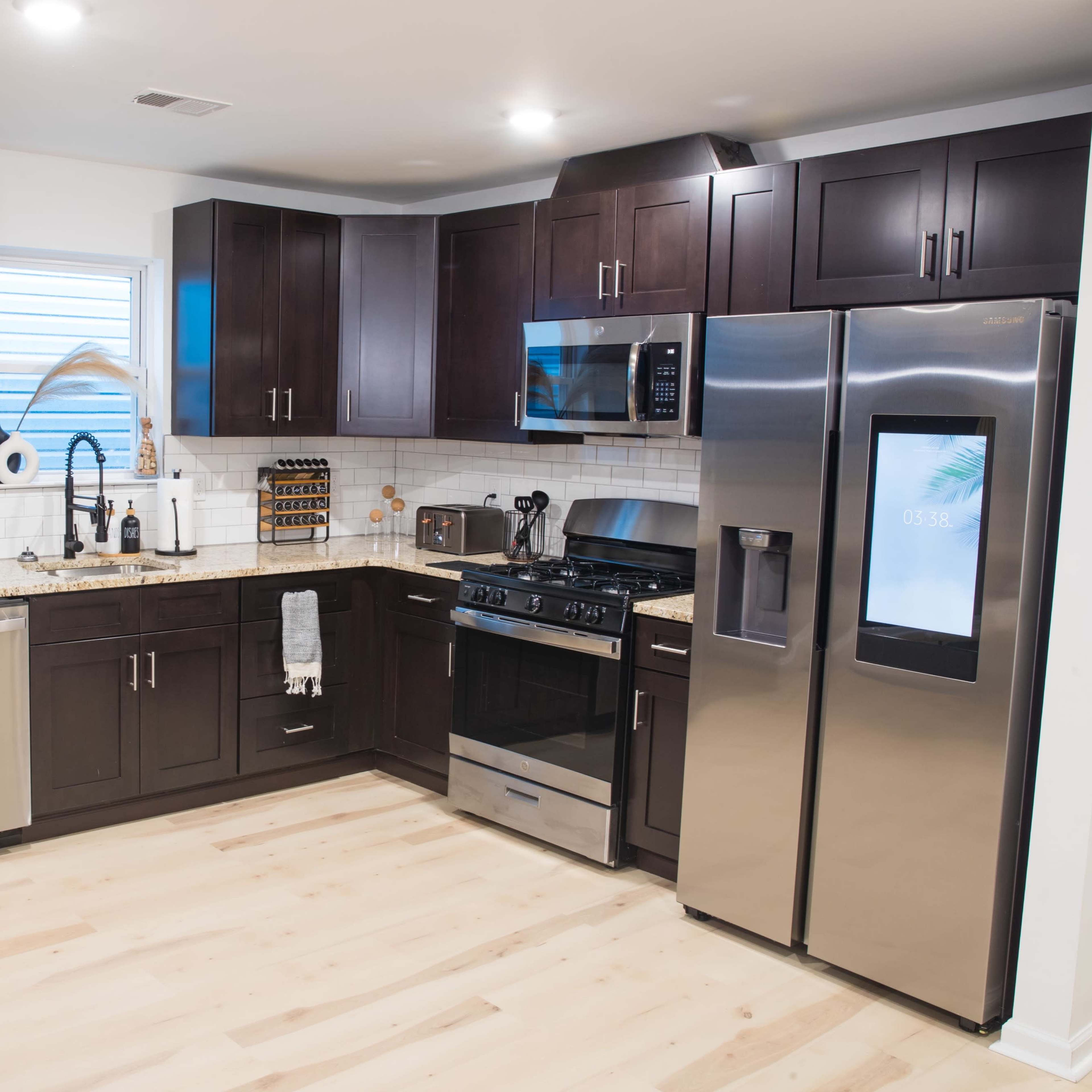 The kitchen features dark wooden cabinets, stainless steel appliances, and a light-colored countertop with a tiled backsplash.