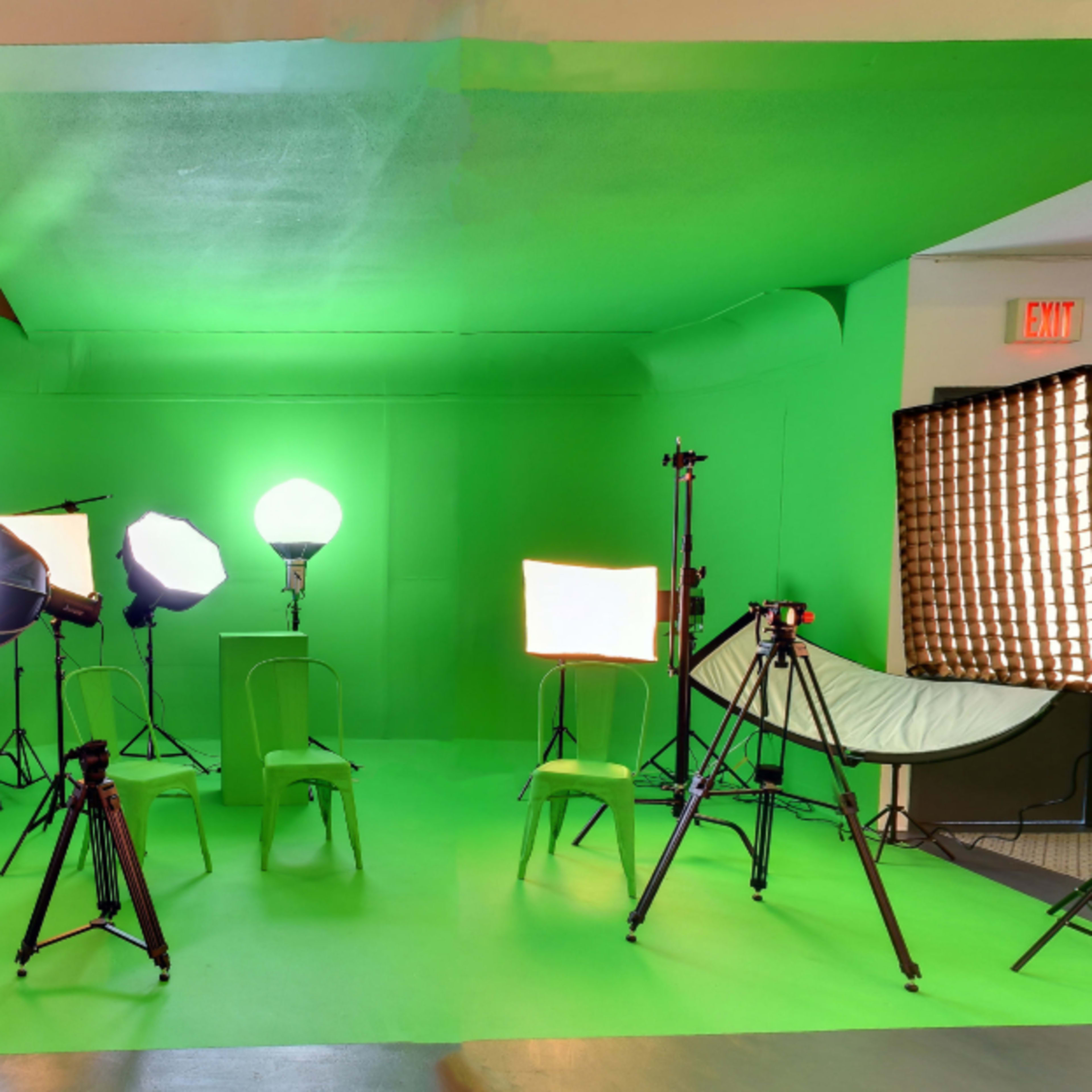 A photography studio equipped with multiple lighting setups and a green backdrop.
