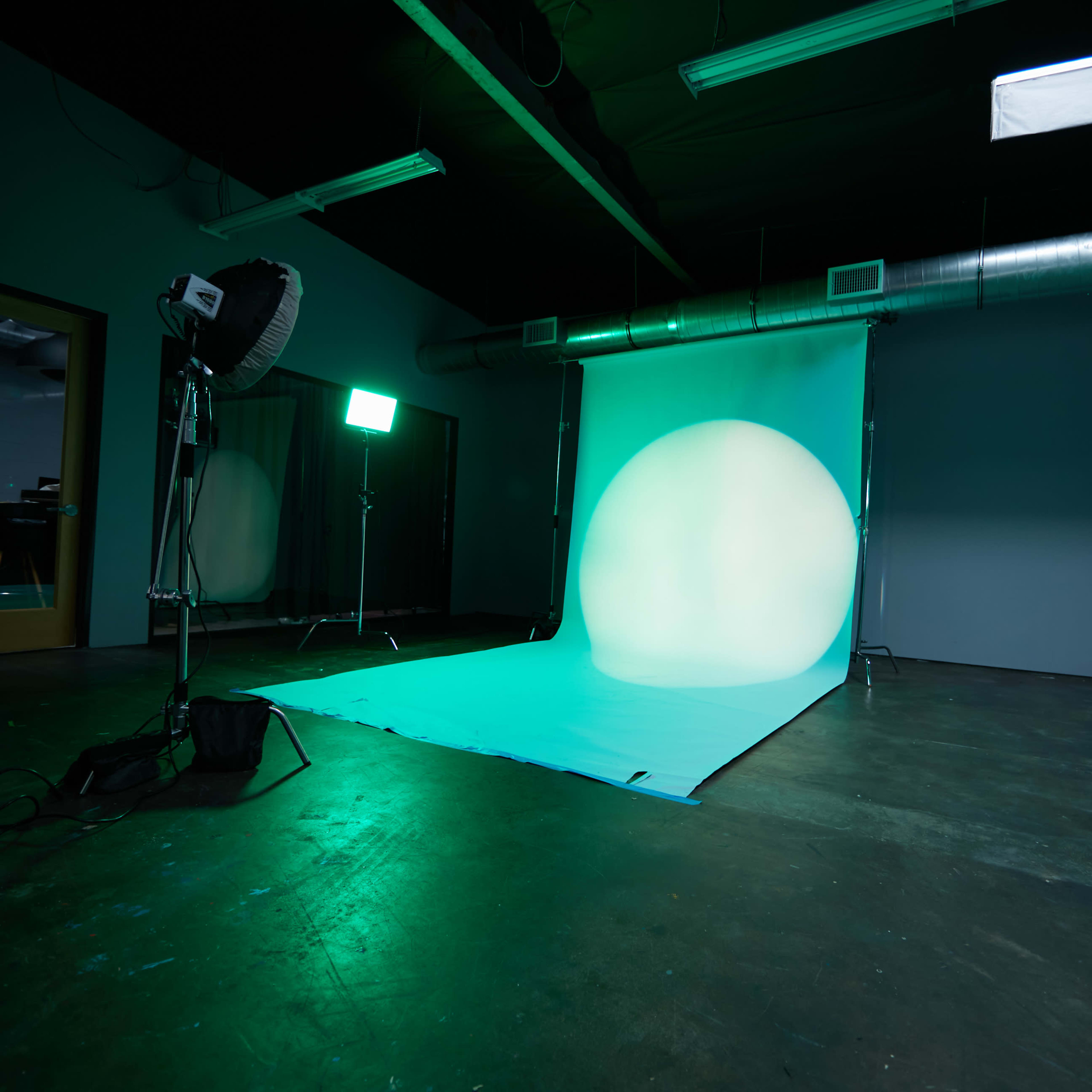 A photography studio features a backdrop with a large circular light and equipment set up for a photoshoot.