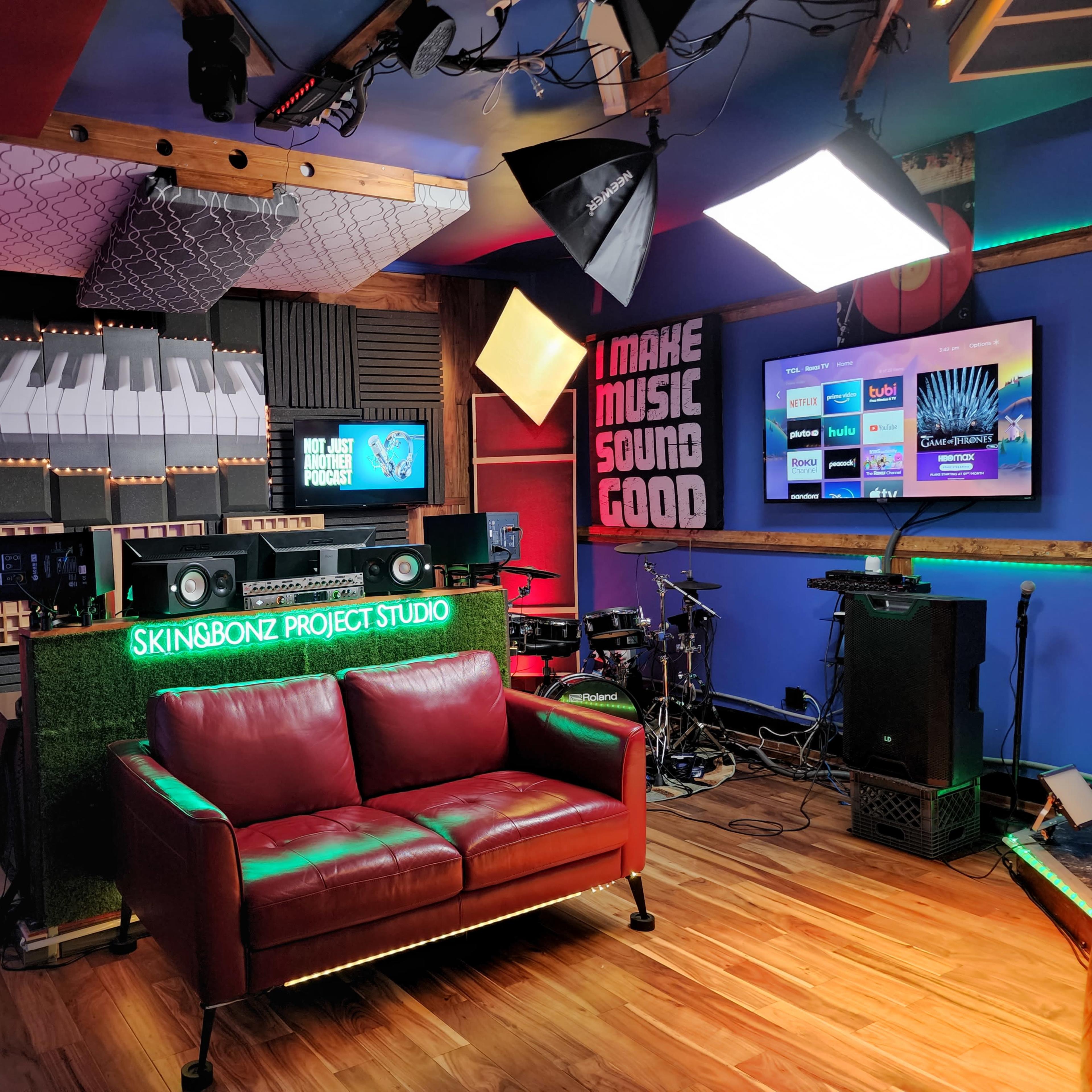 A vibrant music studio with a red leather couch, audio equipment, and multiple screens displaying music-related content.