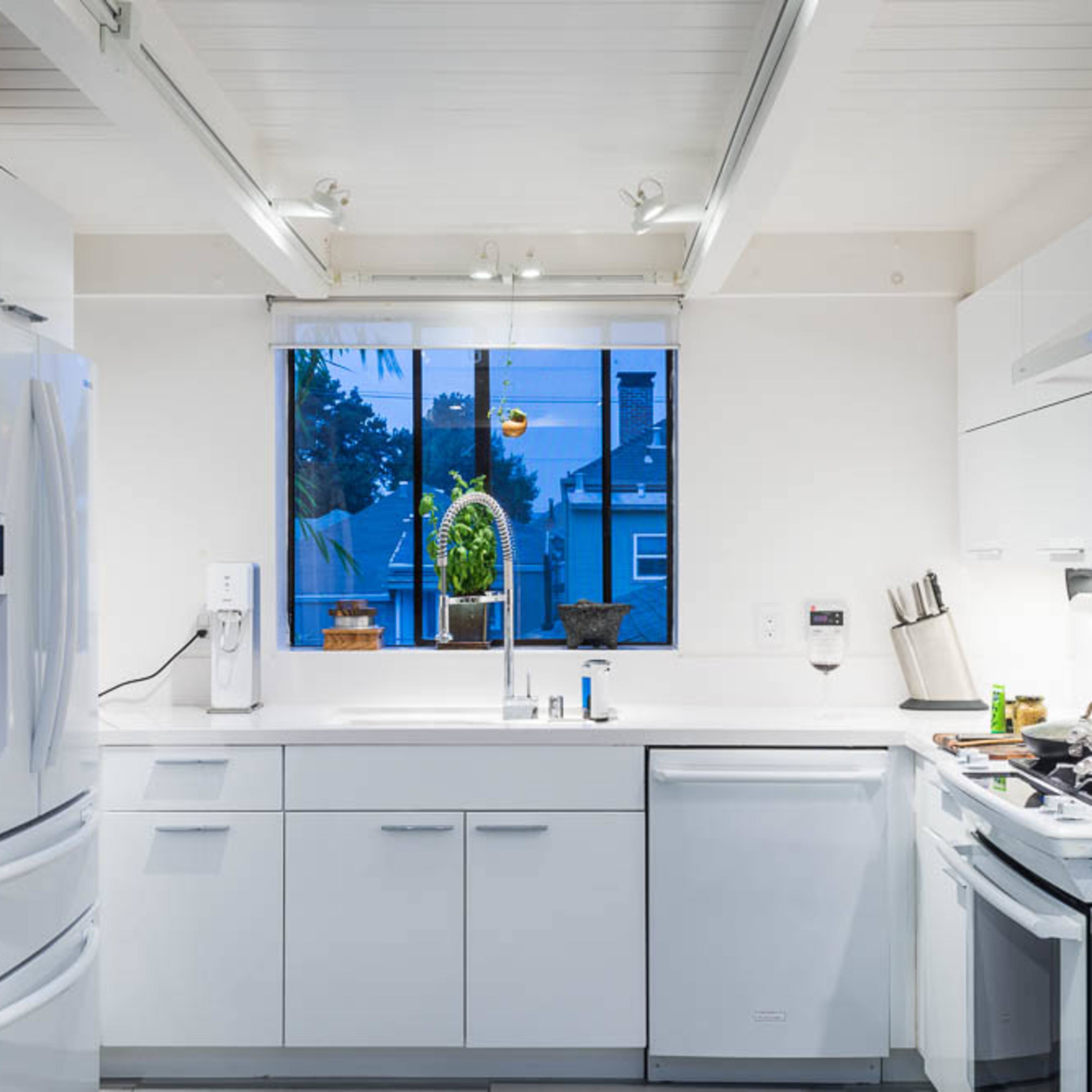 A modern kitchen features white cabinets, a window with a view, and appliances including a refrigerator and stove.