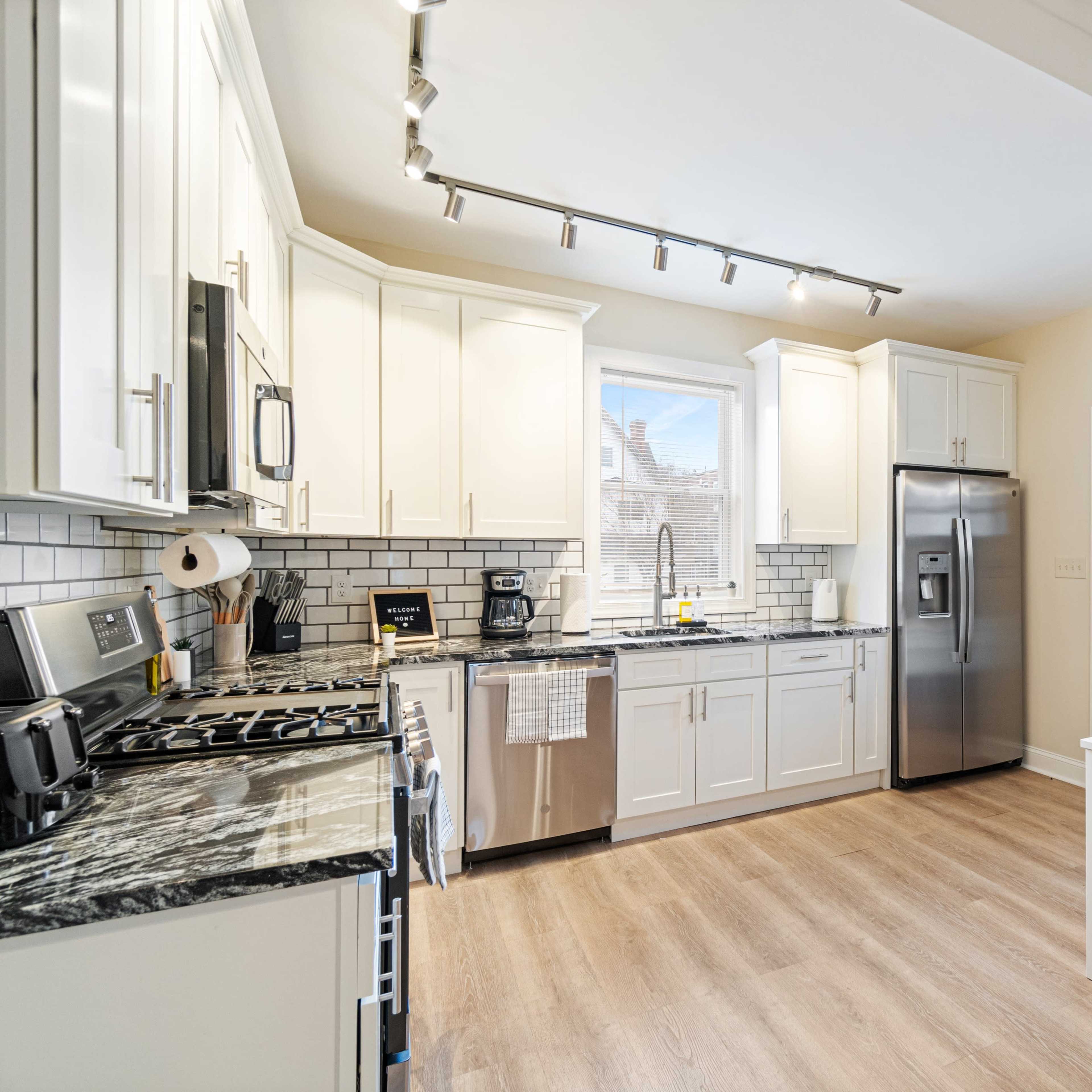 A modern kitchen with white cabinets, stainless steel appliances, and a dining table set for four.