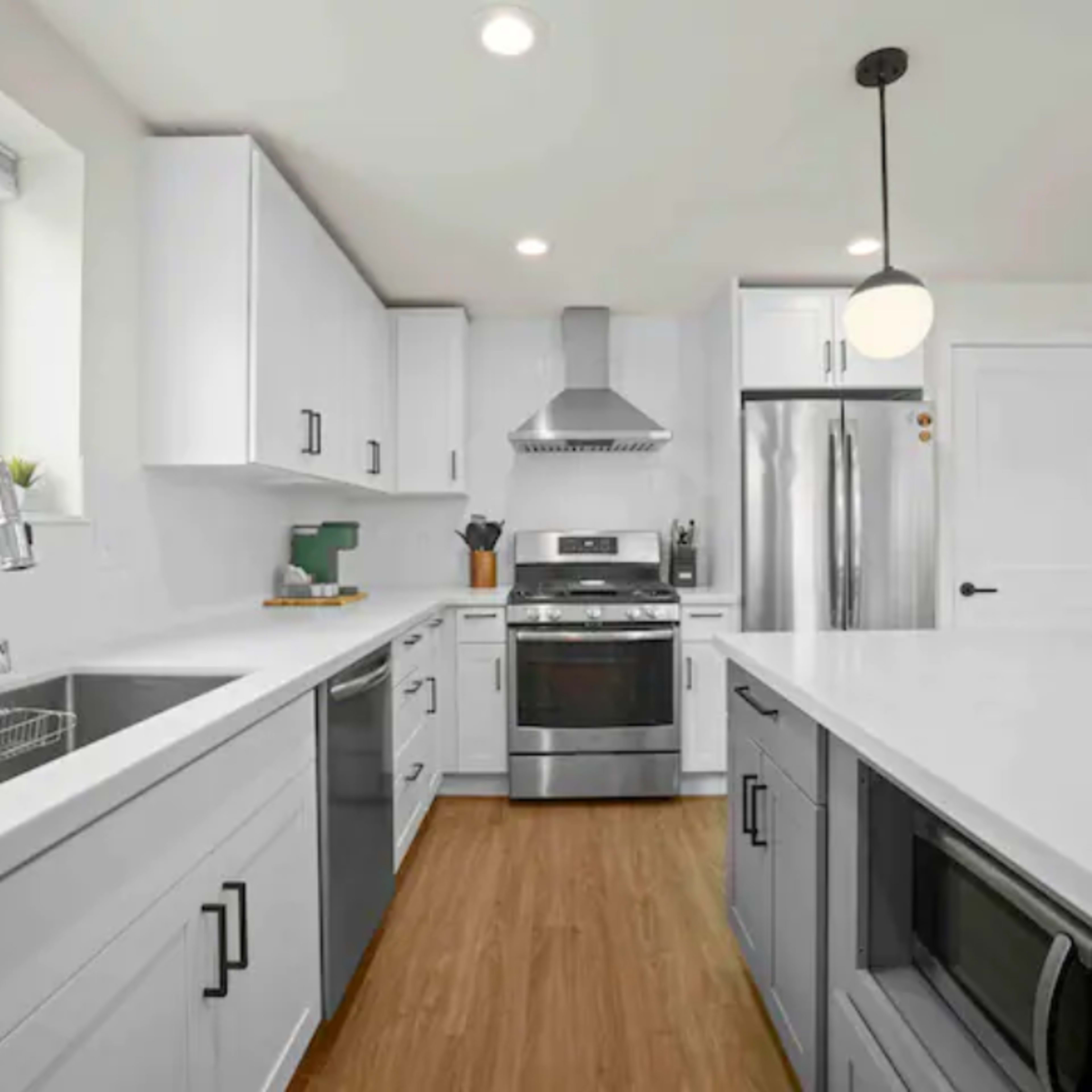 The kitchen features white cabinetry, stainless steel appliances, and a large island with a sink and a microwave.