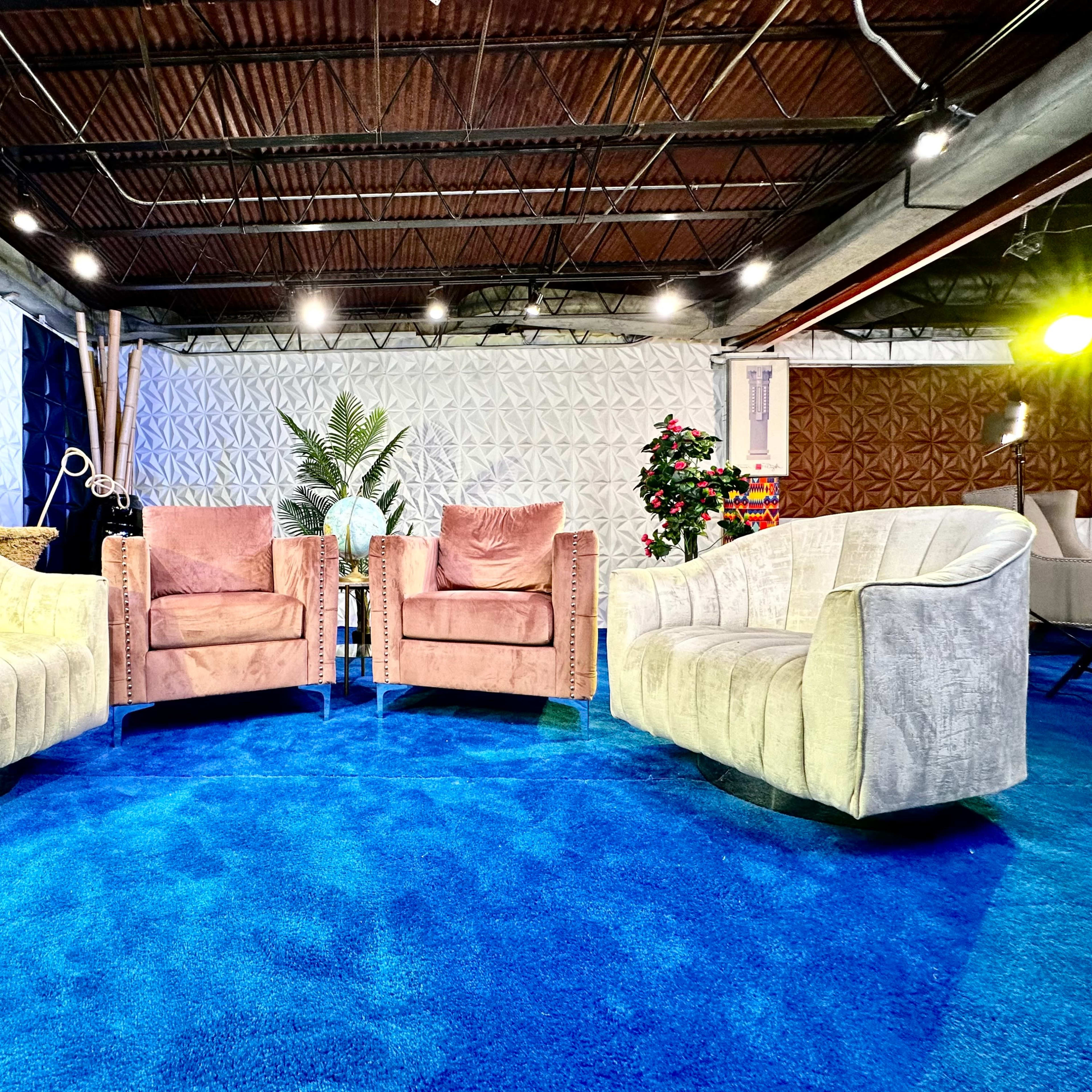A seating area with two armchairs positioned across from each other on a blue carpet, surrounded by textured walls and greenery.