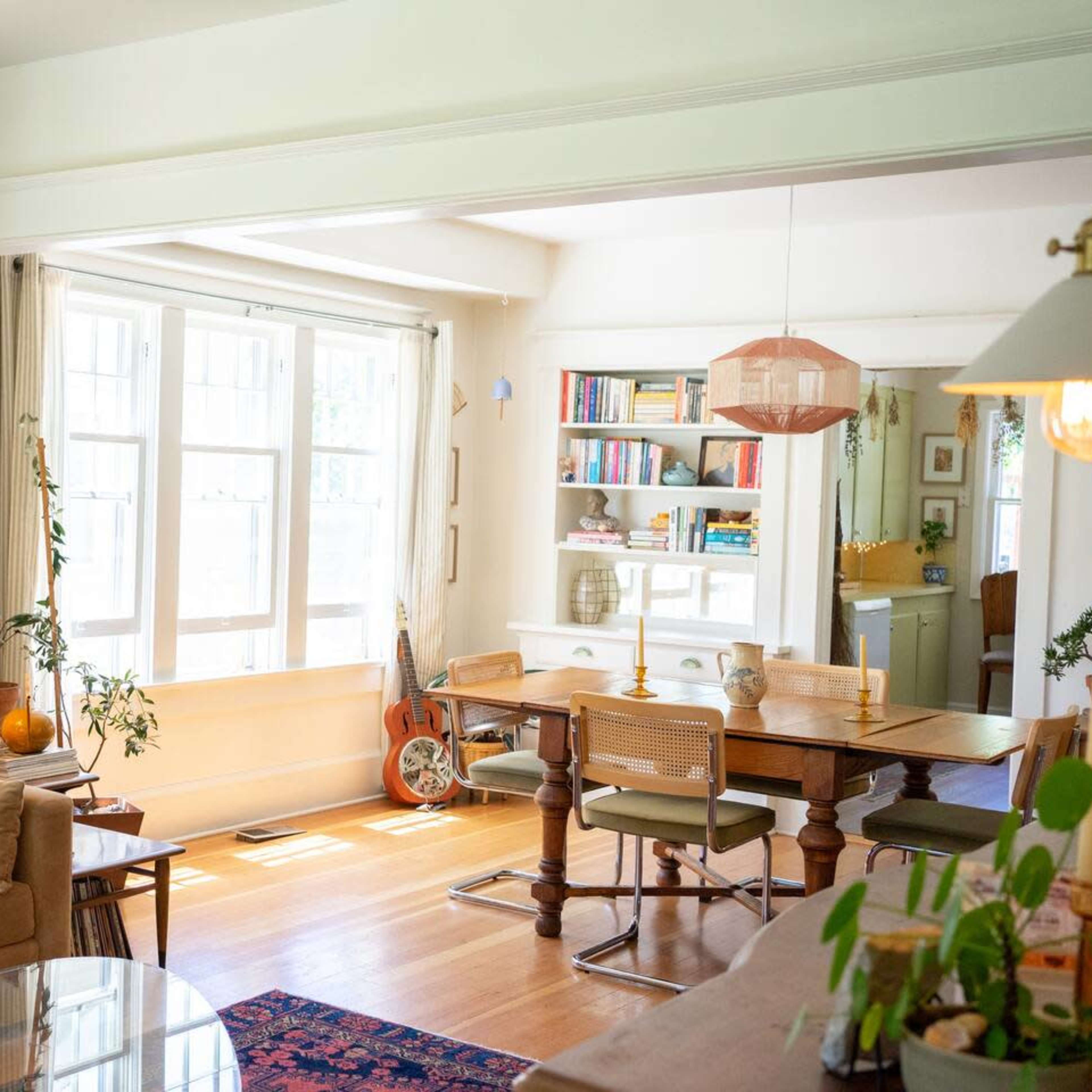 A bright living space with a beige couch, a wooden dining table, and large windows allowing natural light to fill the room.