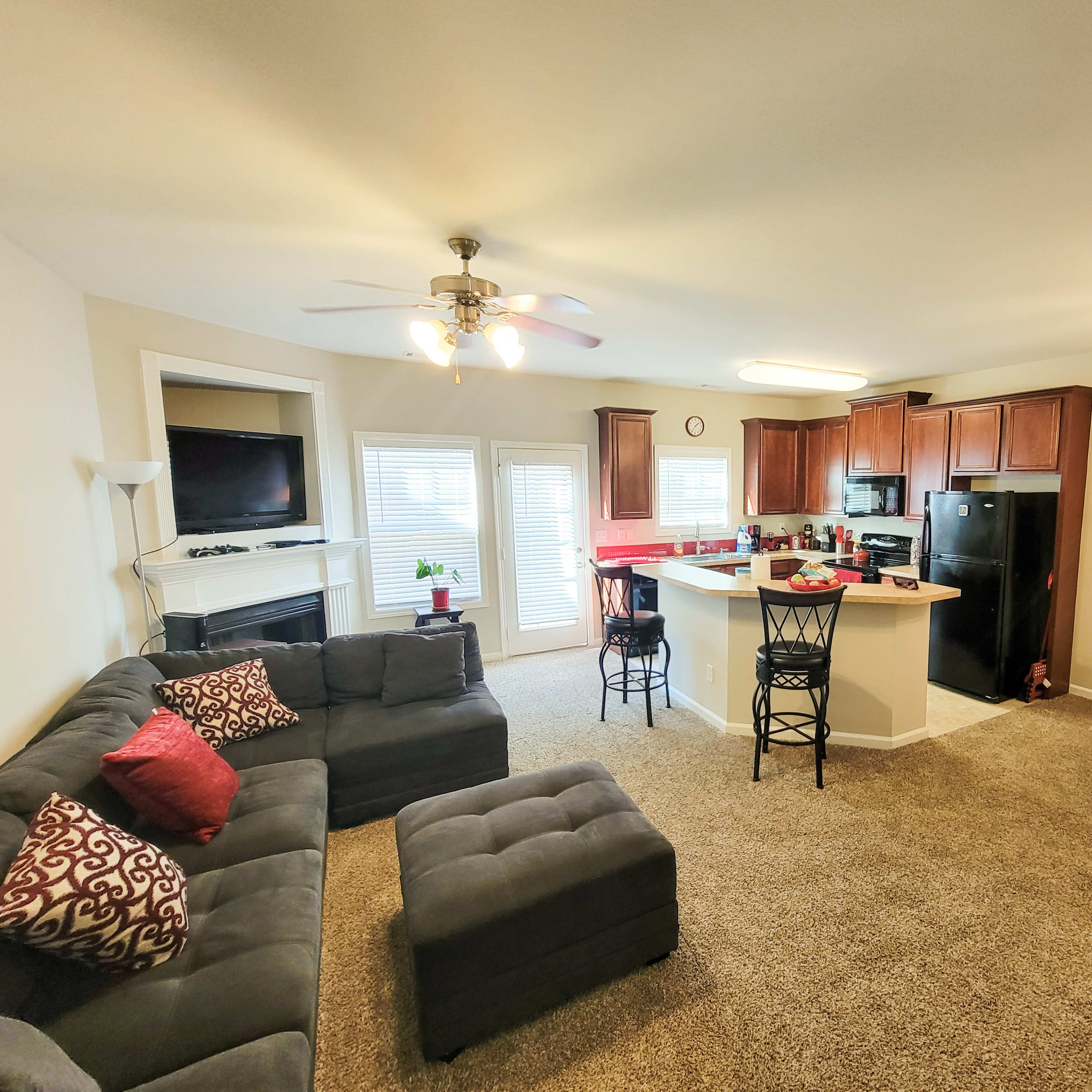 A living area with a sectional sofa, a kitchen with wooden cabinets, and a dining space featuring a round table and chairs.