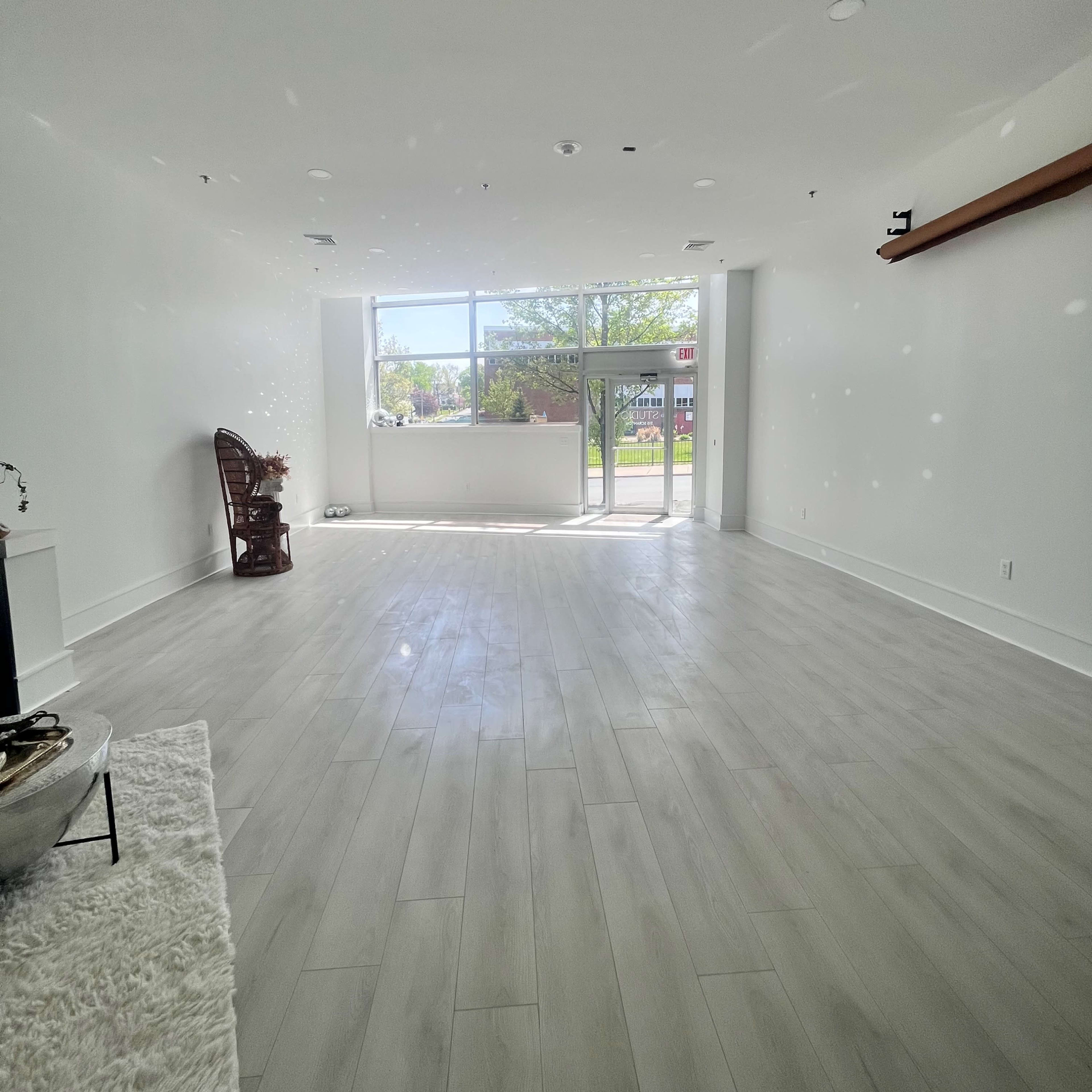 A spacious, empty room with large windows letting in natural light and a door leading outside.