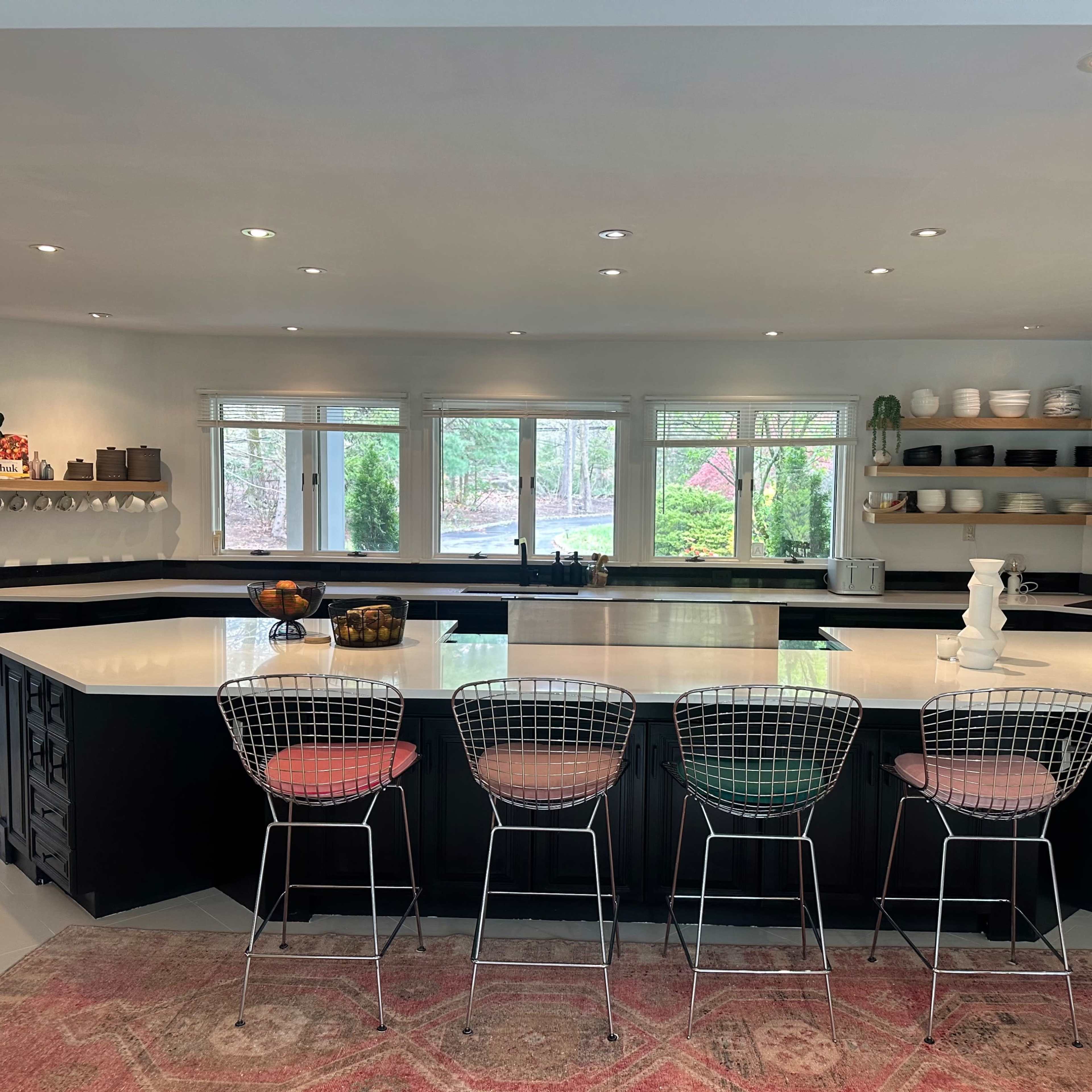 A modern kitchen features a large island with seating, stainless steel appliances, and ample natural light from multiple windows.
